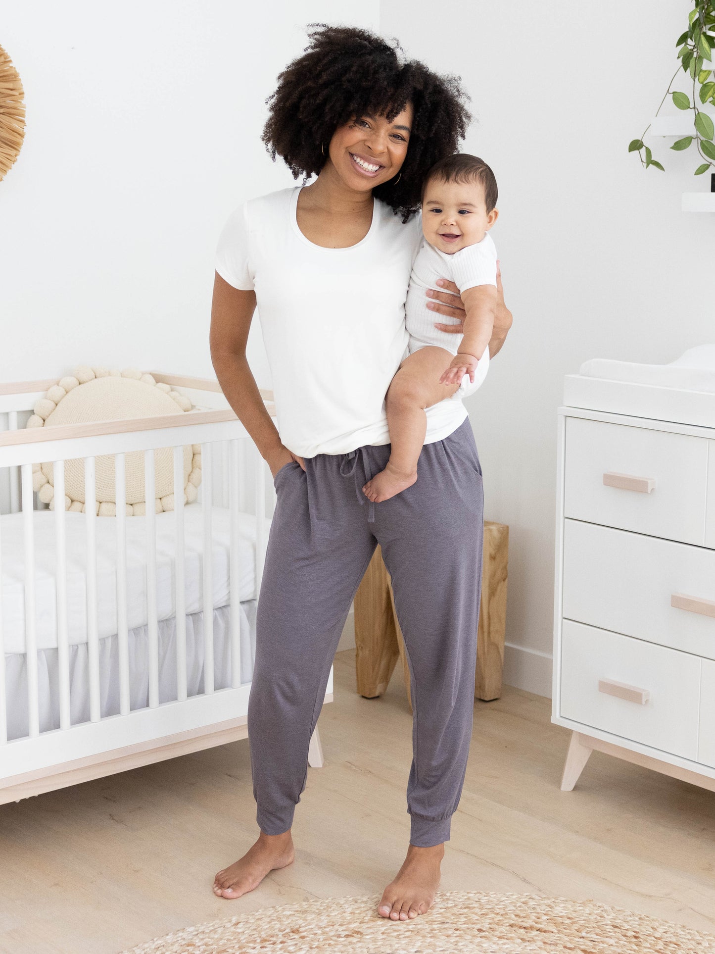 Model holding her baby while wearing the Everyday Lounge Jogger in Heathered Granite