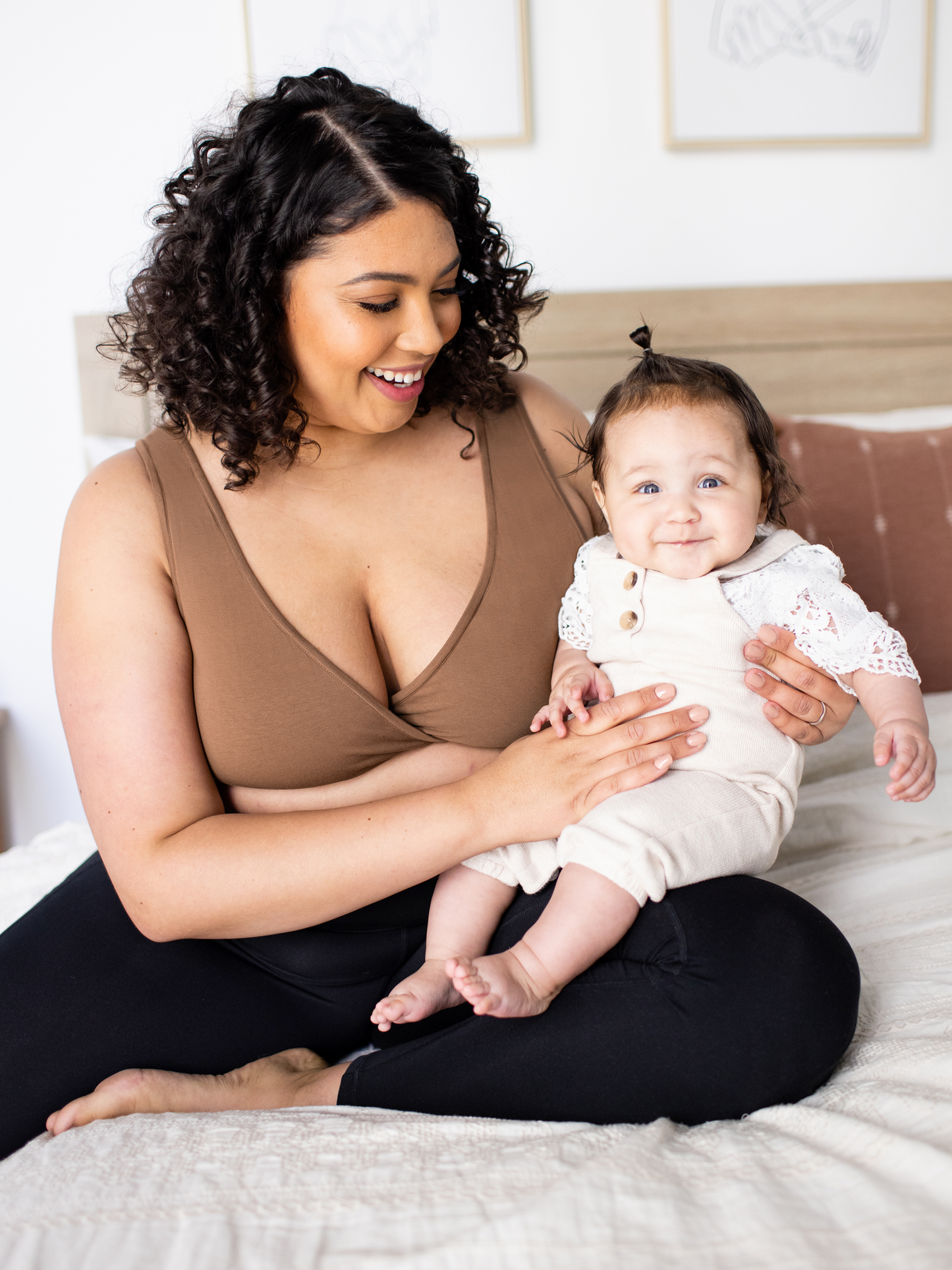 Model sitting and wearing the Organic Cotton Sleep & Nursing Bra  in Mocha, holding baby