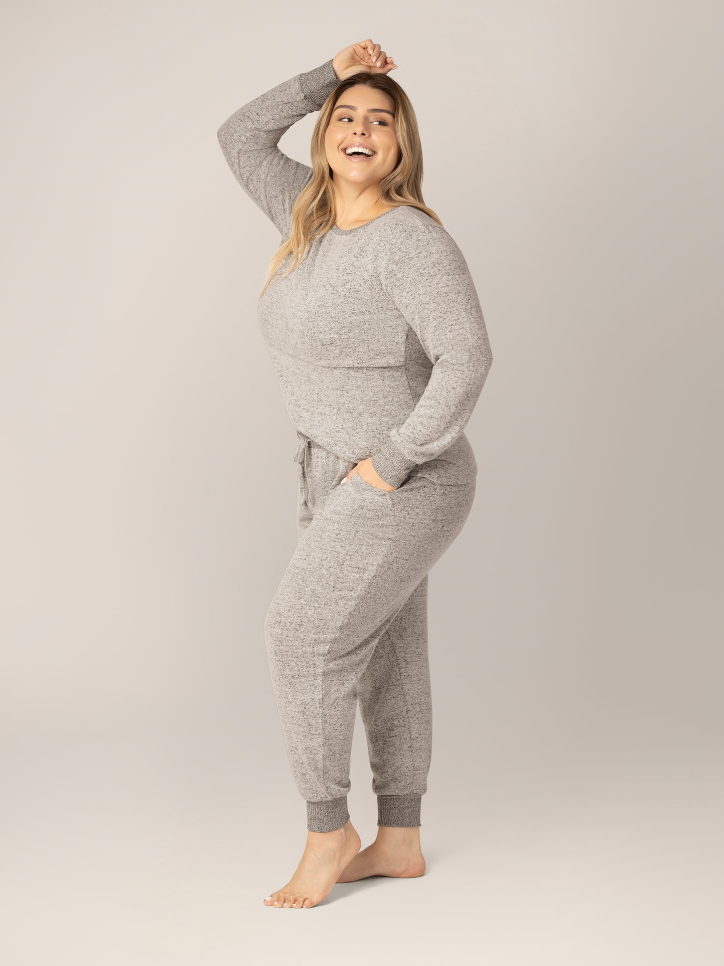 3/4 side view of model wearing the Zoe Nursing Pajama & Lounge Set in Grey Heather, with one hand in pocket and once hand overhead.