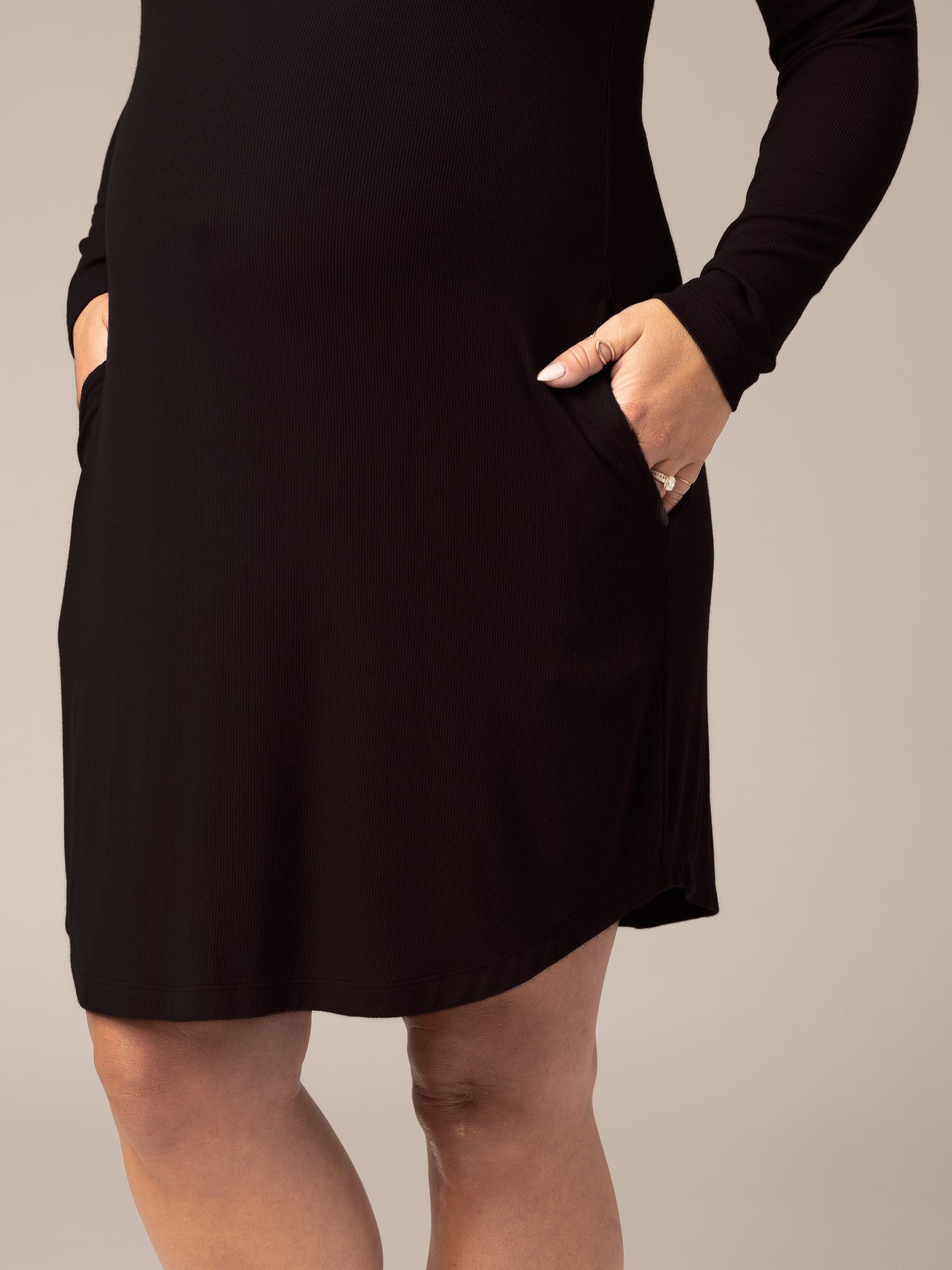 Close up of model wearing the Riley Ribbed Bamboo Maternity & Nursing Nightgown in Black, showing pockets and hem detail; model's hands in pockets