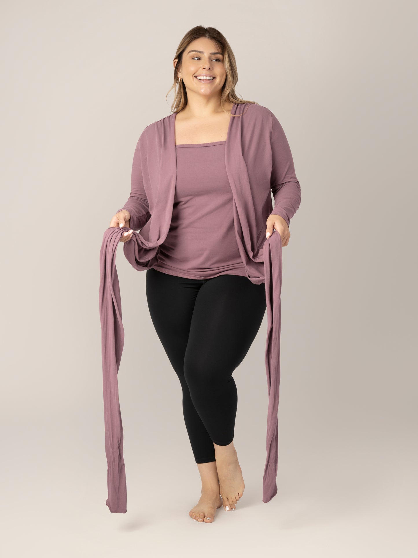 Model wearing the Organic Cotton Skin to Skin Long Sleeve Wrap Top in Twilight, showing top completely unwrapped exposing inner pane and holding straps.@model_info:Vanessa is wearing a Large.