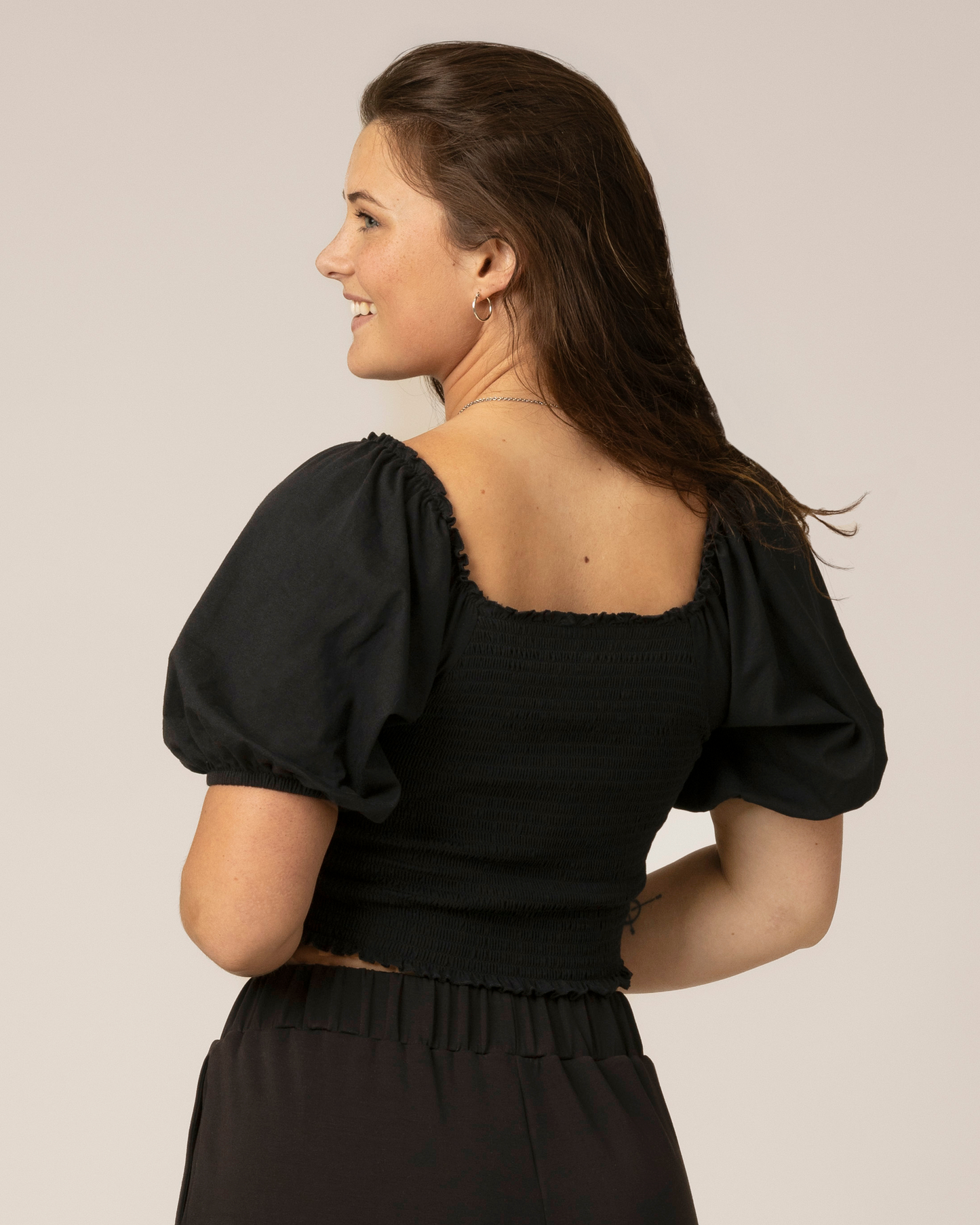 Back view of model wearing Sophia Smocked Cropped Nursing Top in Black 