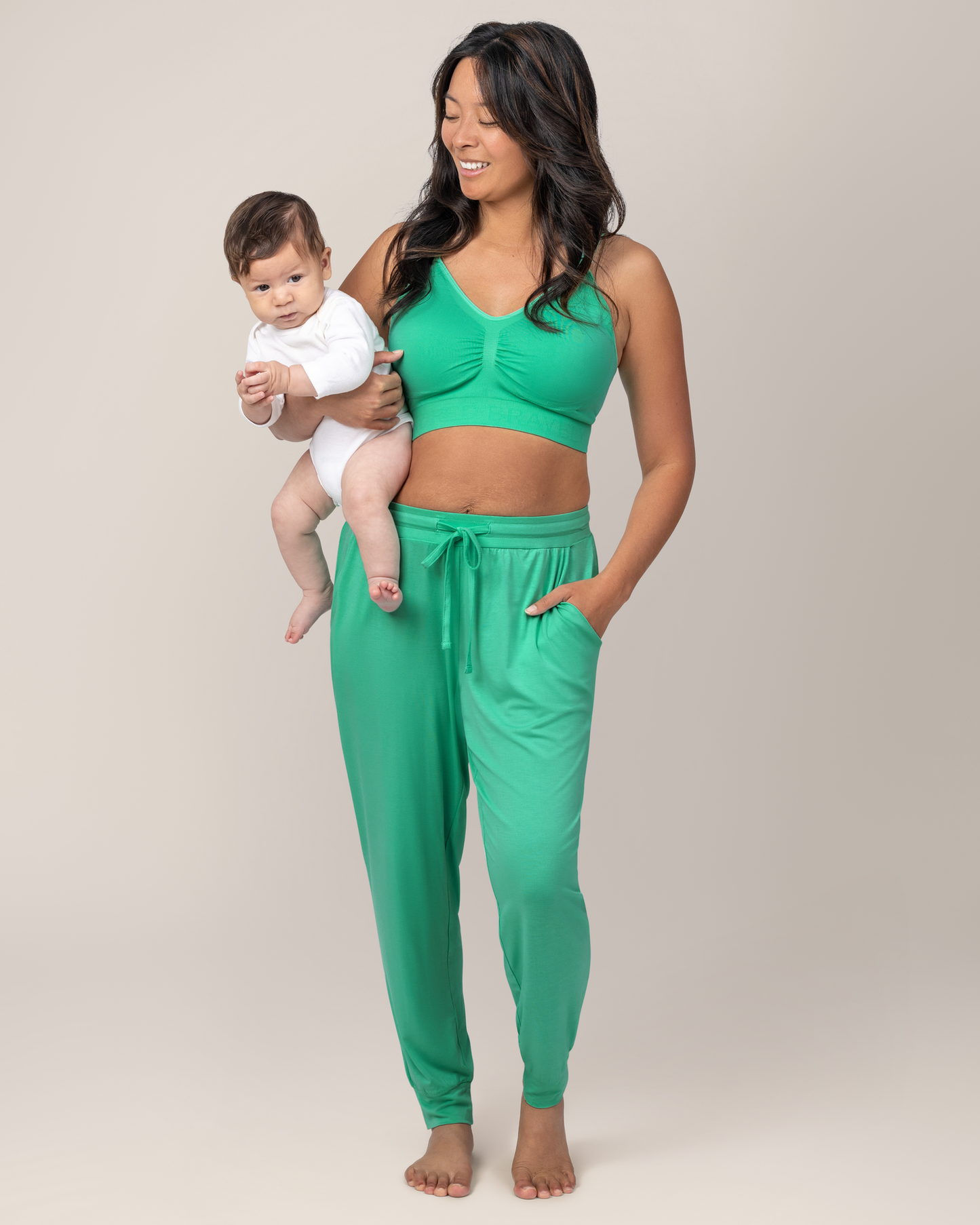 Front view of model holding baby while wearing the Simply Sublime® Nursing Bra in Seafoam with matching Everyday Joggers 