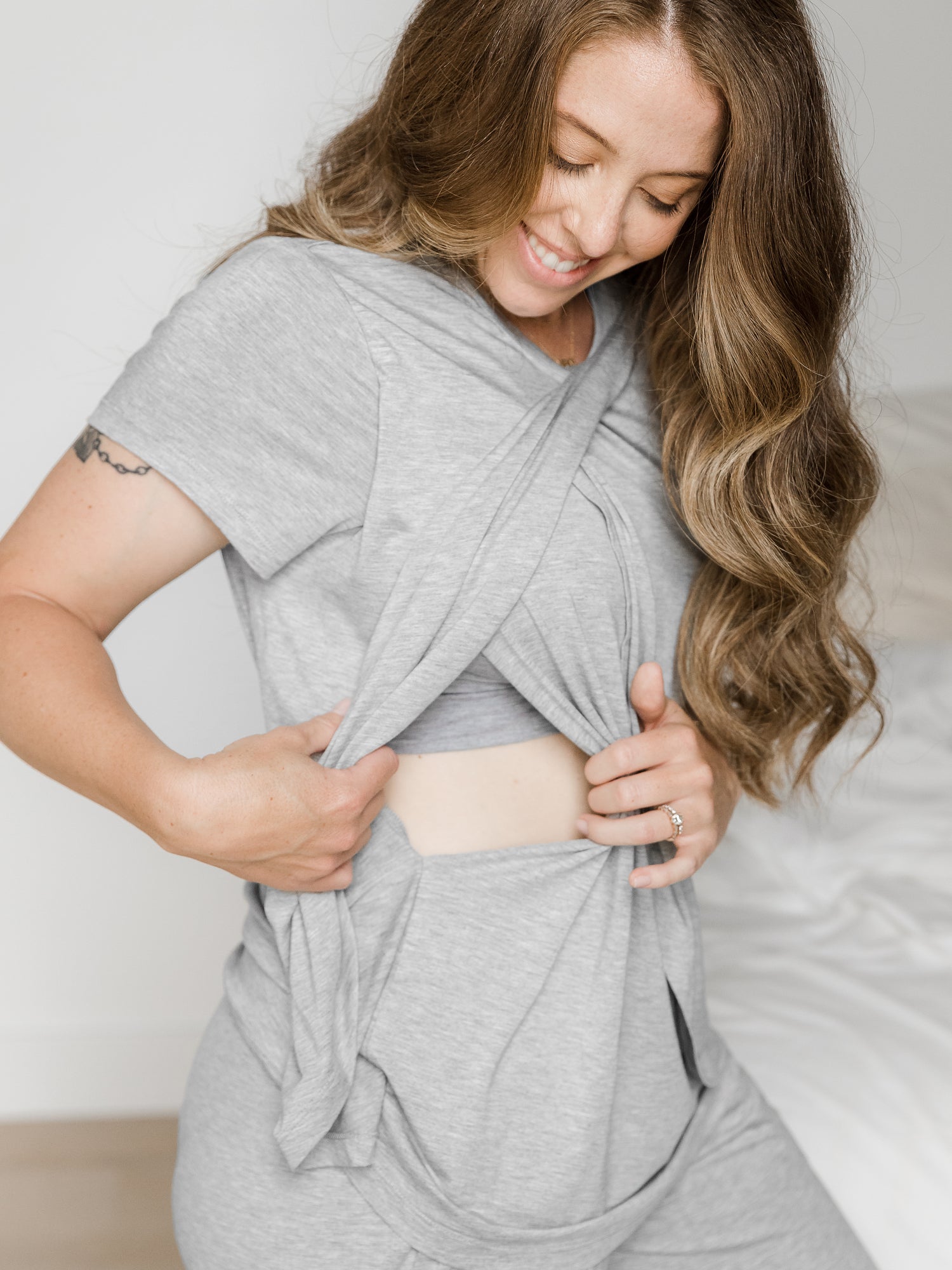 Model showing the nursing access on the Tulip Hem Short Sleeve Pajama Top, which is a part of a maternity pajama set.   @model_info: Ashley is wearing a Small.