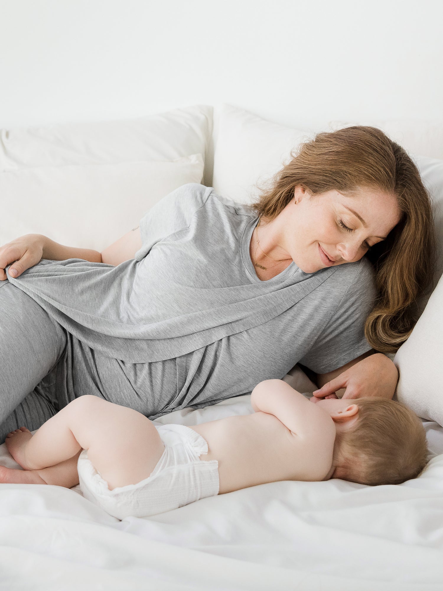 Model laying down with her baby wearing the Tulip Hem Short Sleeve Maternity Pajama Set.
