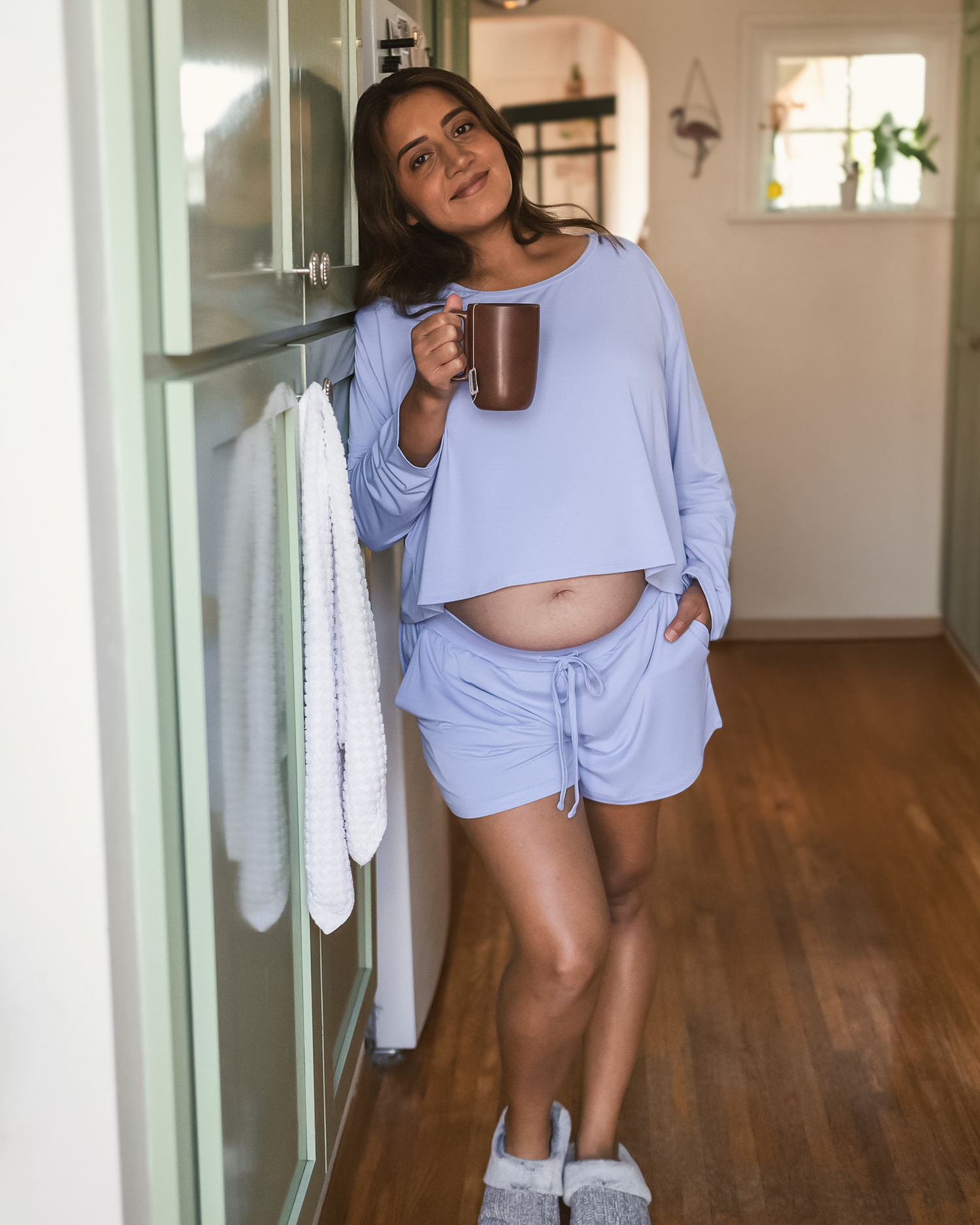 Pregnant model standing in kitchen wearing the Aria Bamboo Casual Cropped Long Sleeve Top in Periwinkle with the matching Aria Bamboo Casual Lounge Short