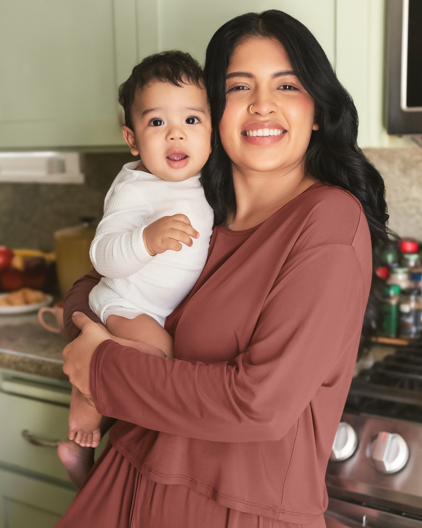 Model standing in kitchen with baby wearing the Aria Bamboo Casual Cropped long Sleeve Top in Redwood with the matching Aria Bamboo Casual Lounge Pant