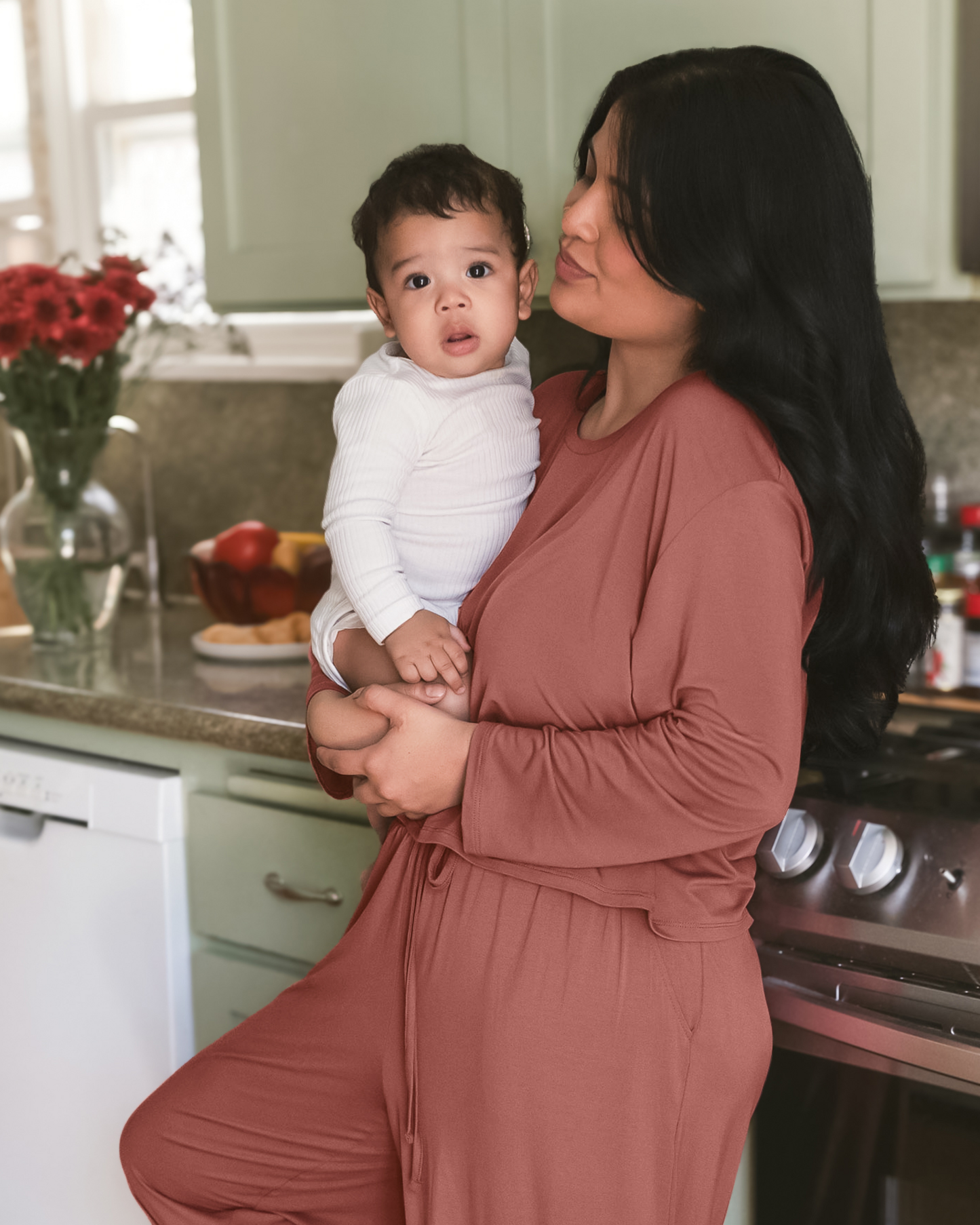 Model standing in kitchen with baby wearing the Aria Bamboo Casual Cropped long Sleeve Top in Redwood with the matching Aria Bamboo Casual Lounge Pant