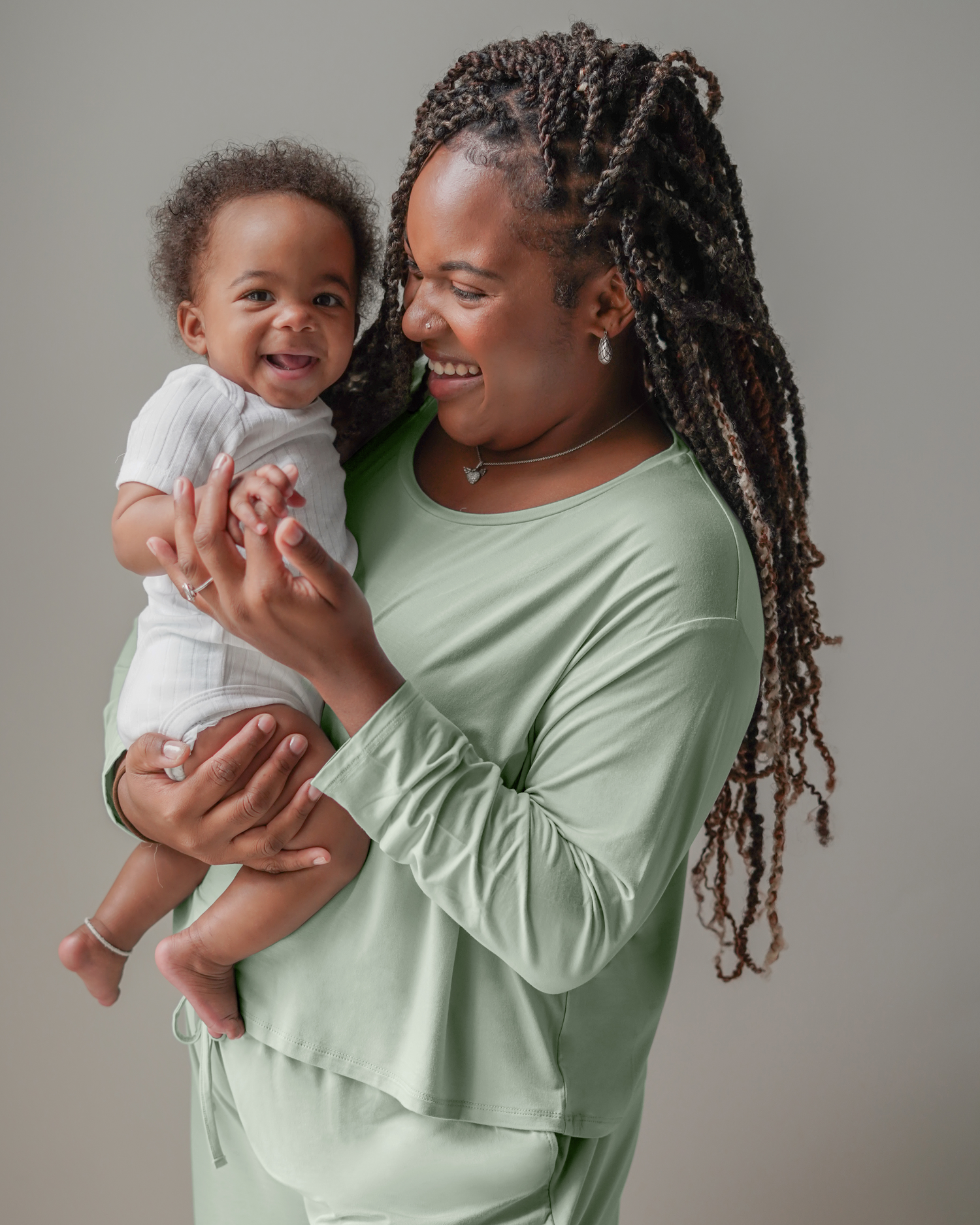 Model wearing the Aria Bamboo Casual Cropped Long Sleeve Top in Aqua Mist, holding baby@model_info:Tonia is wearing a Large.