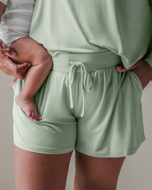 Close up front view of model wearing the Aria Bamboo Casual Lounge Short in Aqua Mist, holding baby.@model_info:Tonia is wearing an X-Large.