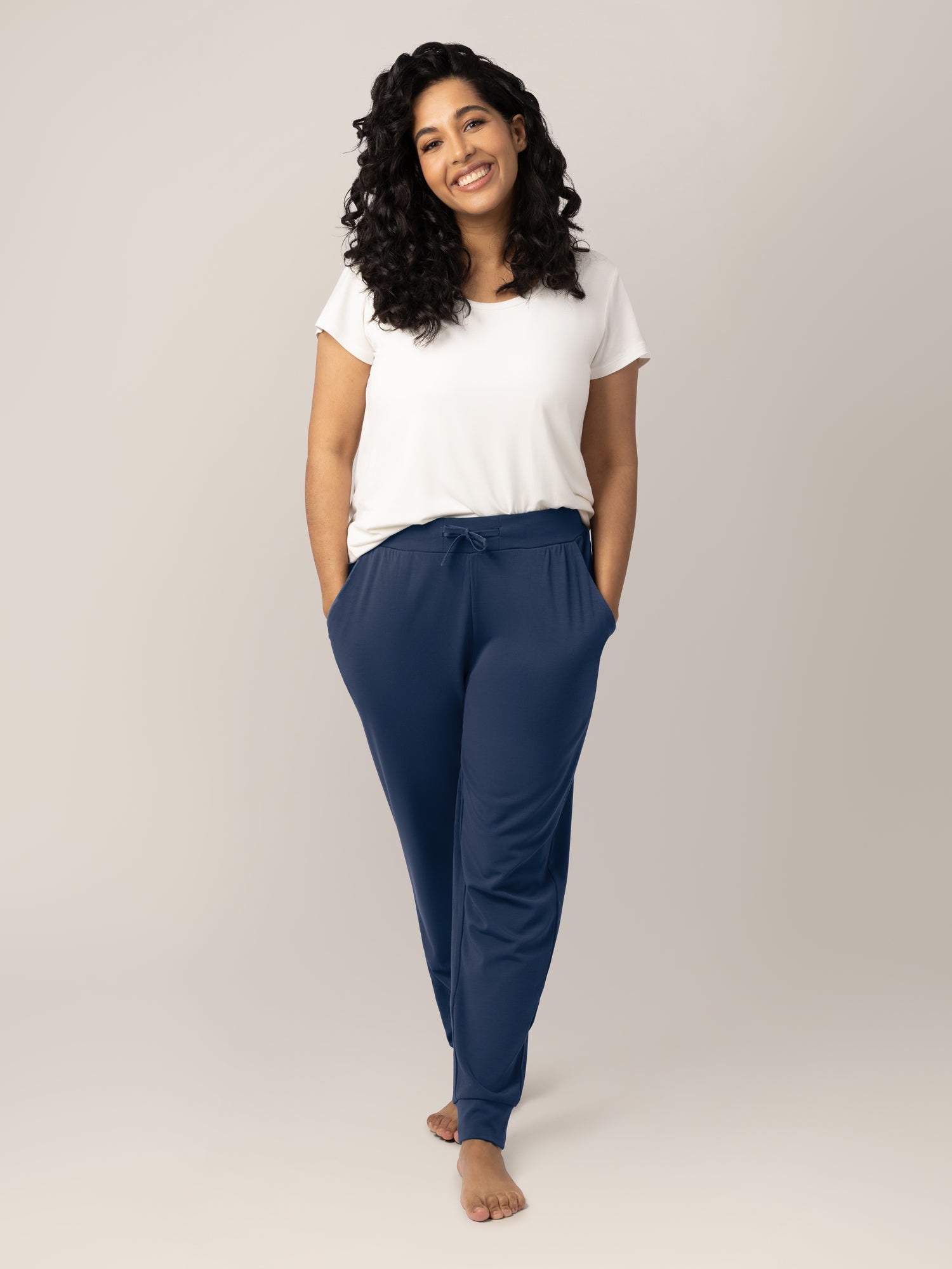 Full body front view of model wearing the Bamboo Maternity & Postpartum Jogger in Navy, paired with the Everyday Maternity & Nursing T-shirt in White. @model_info:Zakeeya is 5'2" and wearing a Small.