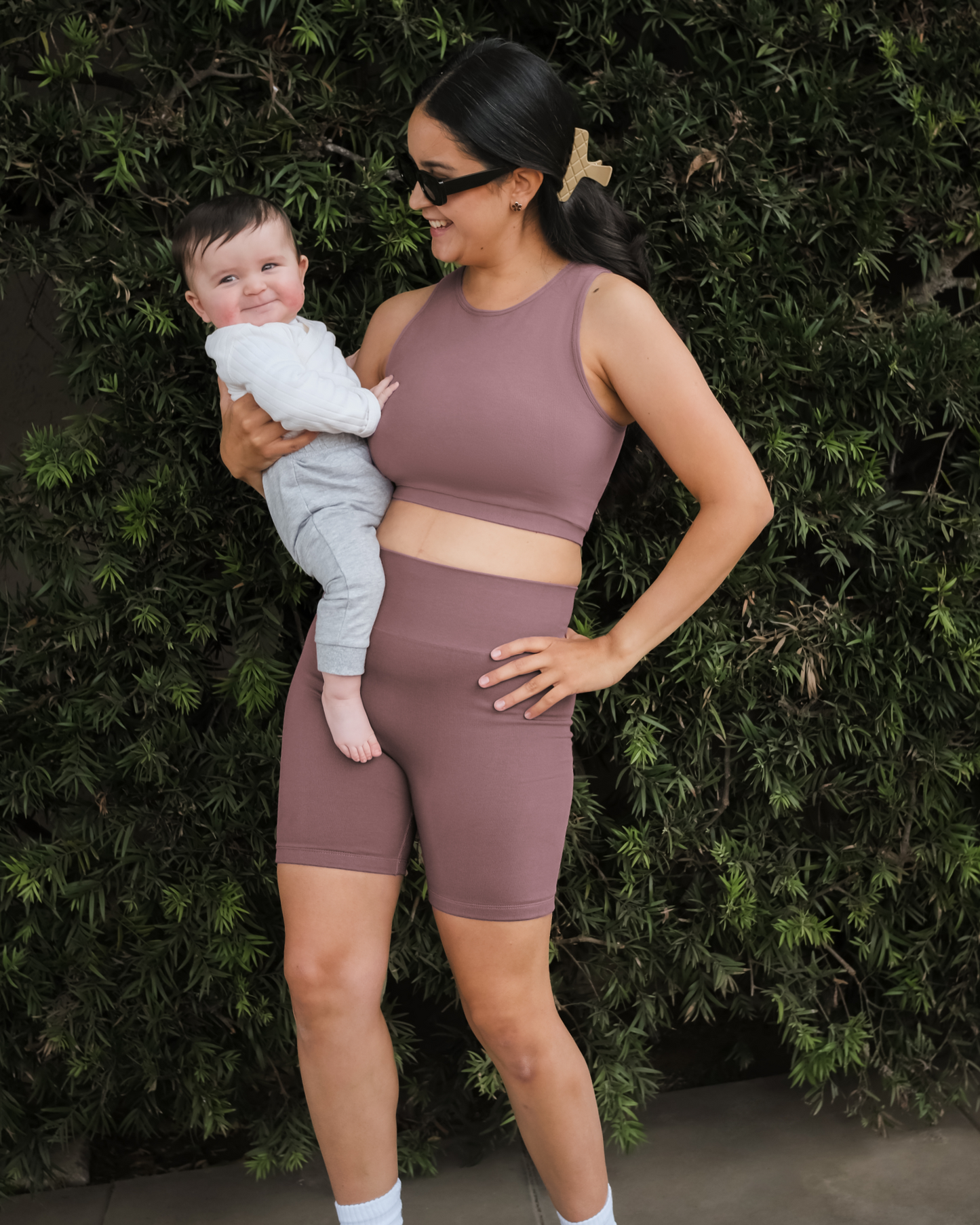 Model outside holding baby and wearing the Sublime® Bamboo Maternity & Postpartum Bike Short in Twilight paired with matching Sublime® Bamboo Hands-Free Pumping Longline Bra Top
@model_info:Dama is wearing a Medium.