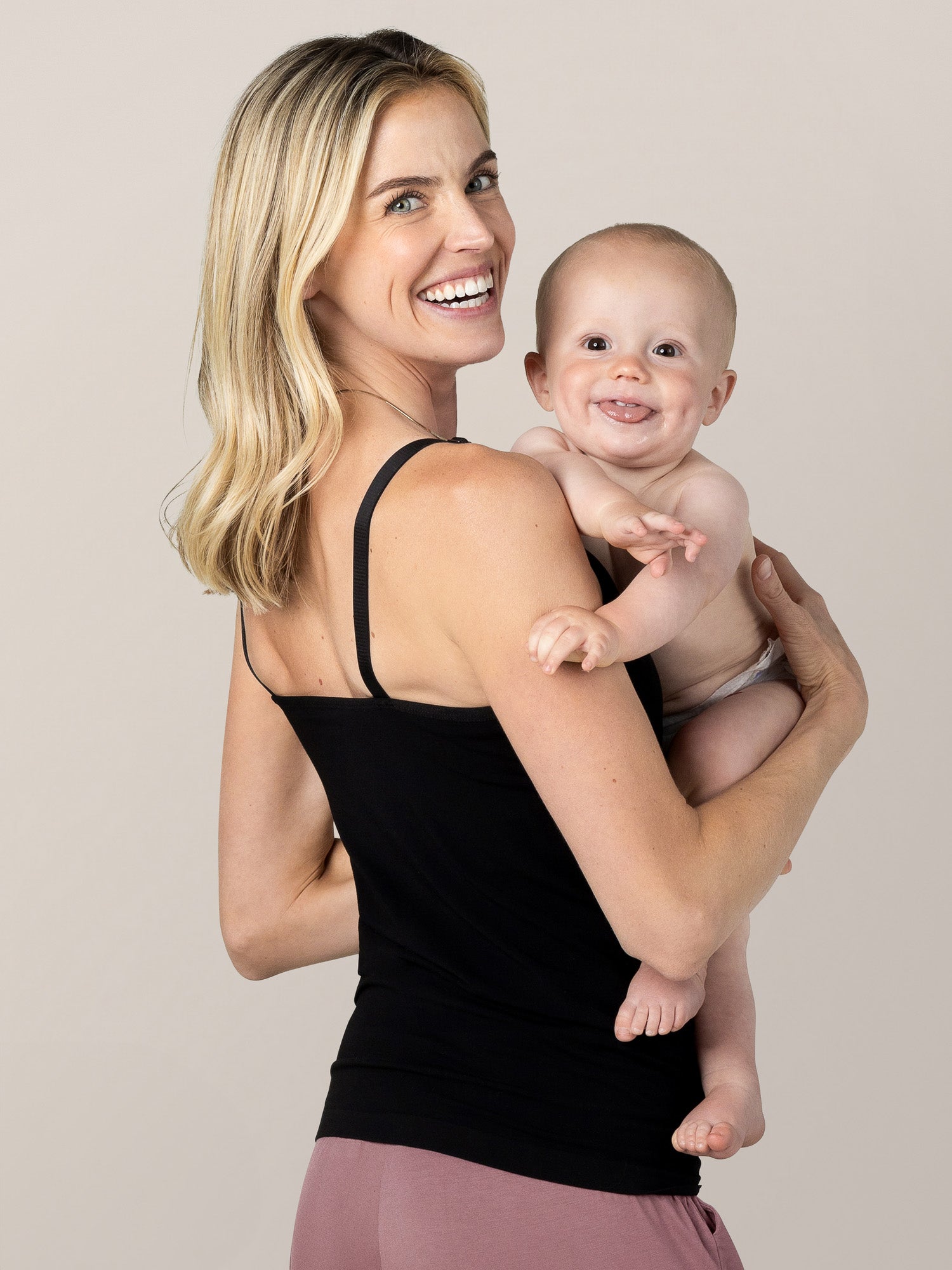 Model holding a baby and wearing the Sublime® Bamboo Hands-Free Pumping & Nursing Camisole in Black
