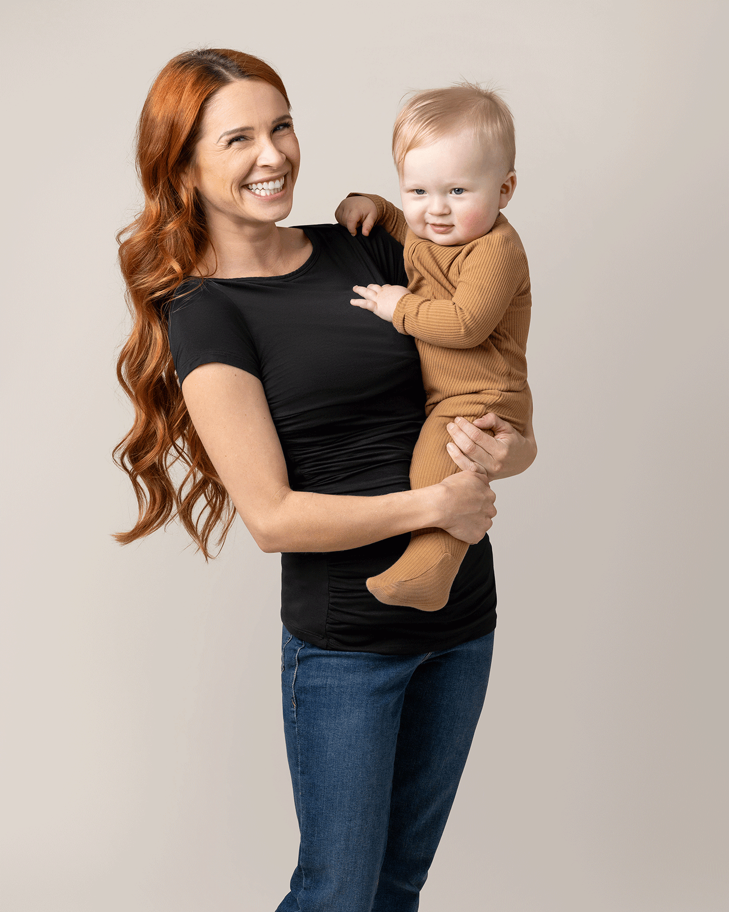 Front view of model wearing Kiera Boat Neck Maternity & Nursing Top in Black, holding baby