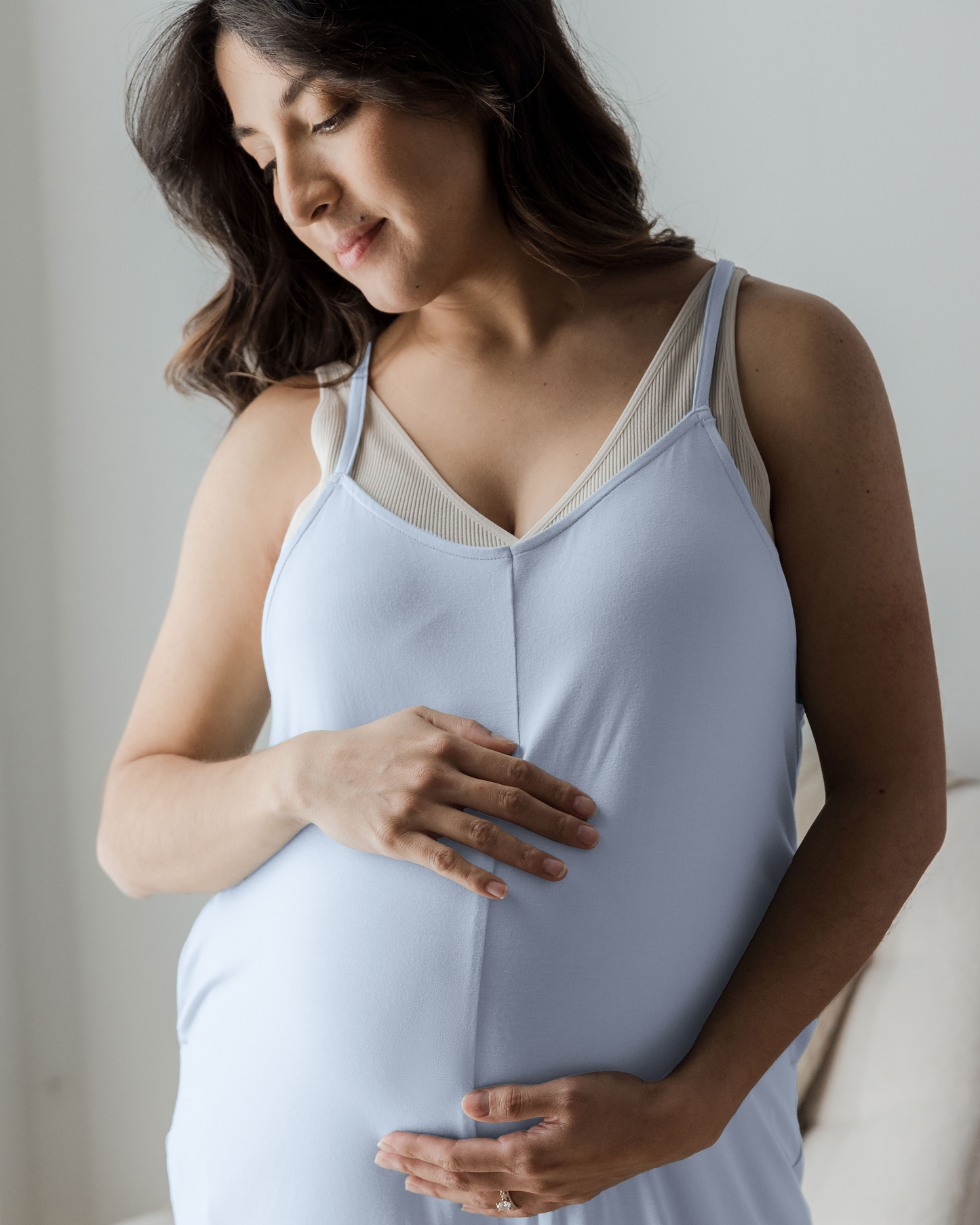 Close up shot of pregnant model with hand on belly wearing the Charlie Maternity & Nursing Romper in French Blue, paired with Sublime® Adjustable Crossover Nursing & Lounge Bra in Stone 