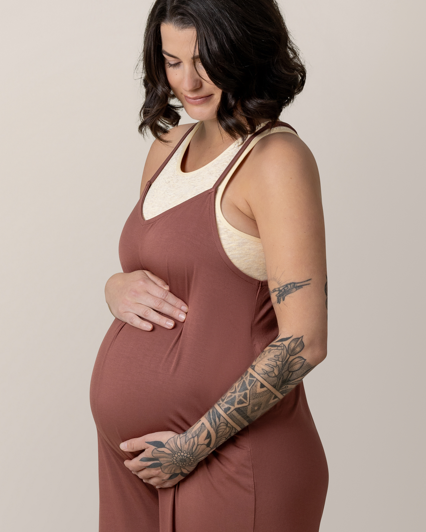 Close up of pregnant model with hands cradling belly, wearing the Charlie Maternity & Nursing Romper in Redwood, paired with Sublime® Bamboo Maternity & Nursing Longline Bra Top in Oatmeal Heather