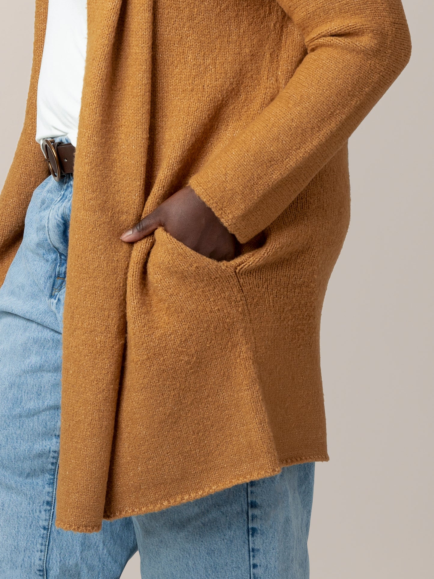 Close up view of model wearing the Chloe Cardigan Sweater in Chai, showing pocket and hem detail.