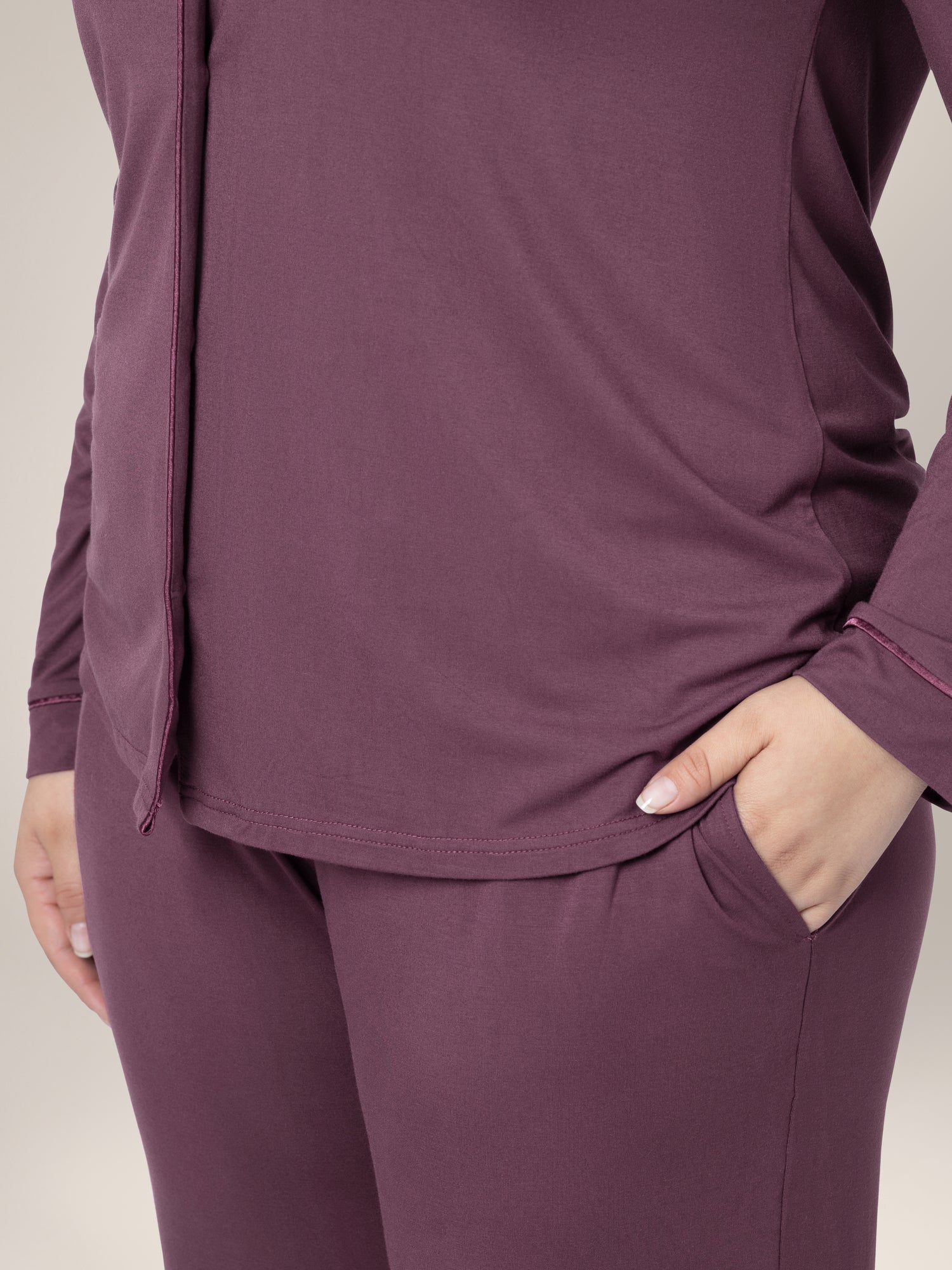 Close up of model wearing the Clea Bamboo Long Sleeve Pajama Set in Burgundy Plum, showing shirt hem and pocket on bottoms.\