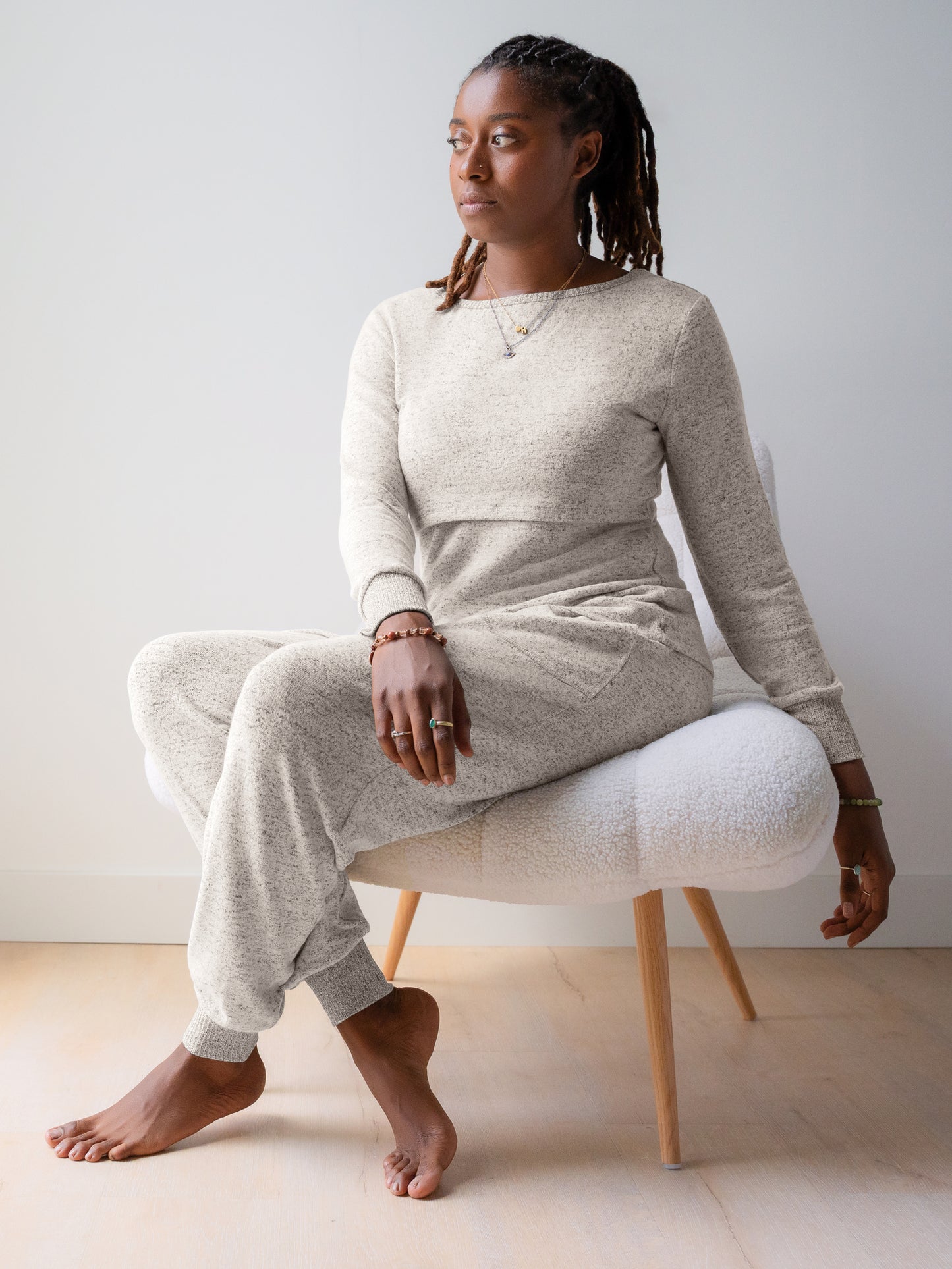 Model sitting on chair wearing the Zoe Nursing Pajama & Lounge Set in Grey Heather. @model_info:Destini is 5'6" and wearing a Medium.