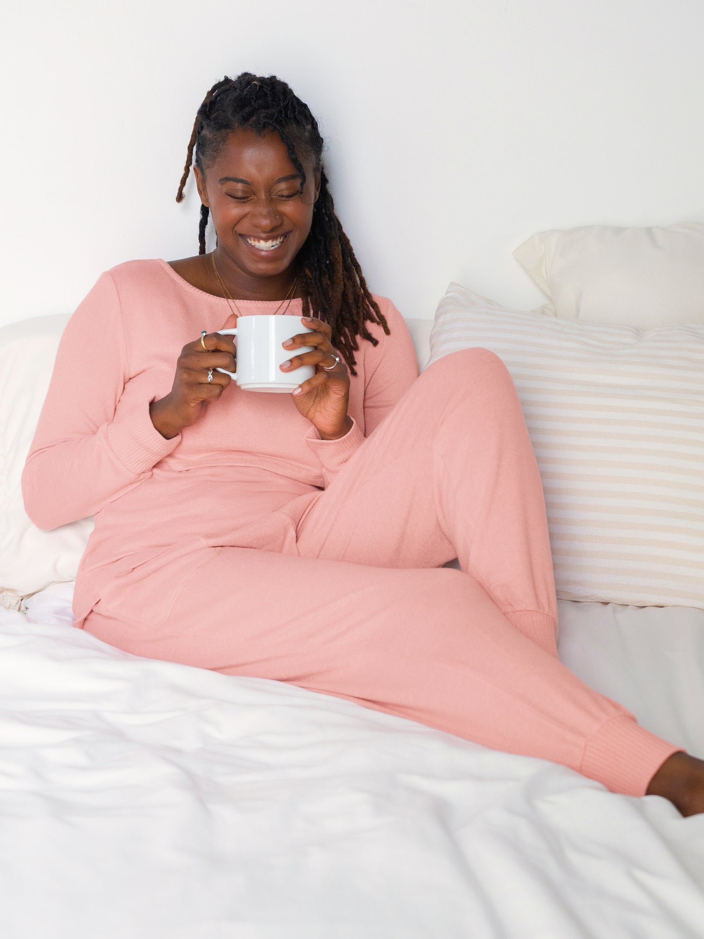 Model lounging on bed holding mug and wearing the Zoe Nursing Pajama & Lounge Set in Rose Heather @model_info:Destini is 5'6" and wearing a Medium.