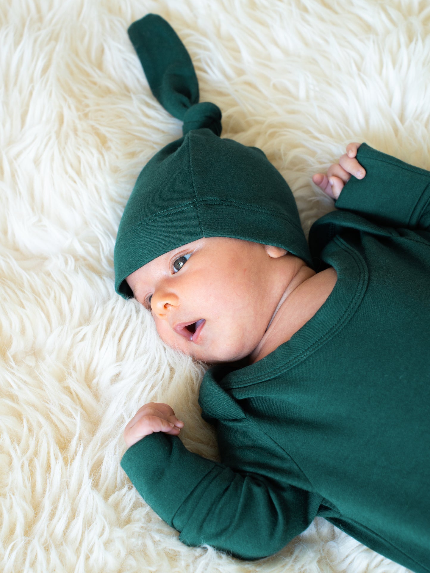 Close up of newborn wearing the Baby Knotted Gown & Hat Set in Evergreen.