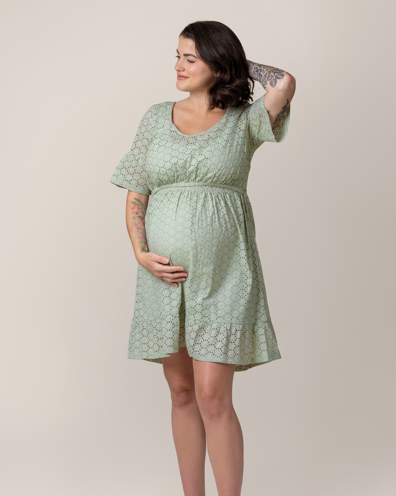 Front view of pregnant model wearing the Dahlia Eyelet Maternity & Nursing Dress in Aqua Mist, with one hand under belly and the other on the back of her head