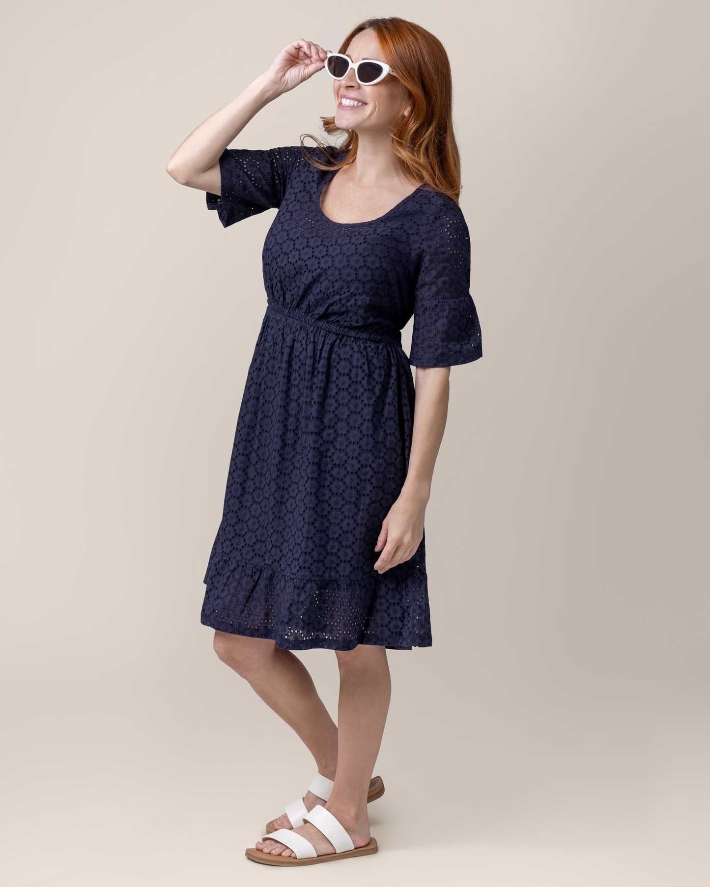 Front angled view of model wearing the Dahlia Eyelet Maternity & Nursing Dress in Navy, paired with sandals @model_info:Shannon is 5' and wearing a Small.