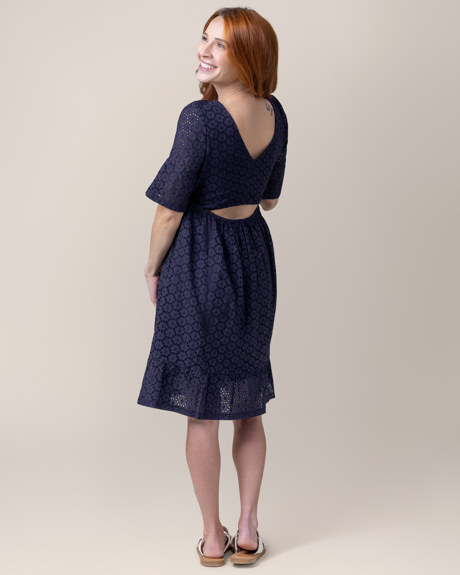 Back view of model wearing the Dahlia Eyelet Maternity & Nursing Dress in Navy, showing cutout