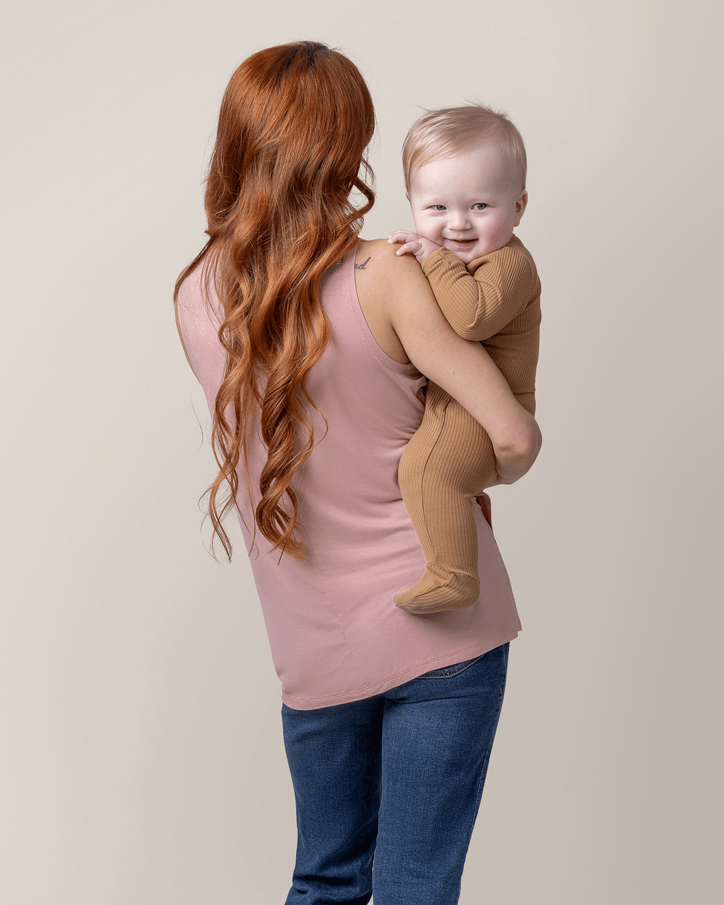 Back view of model holding baby and wearing the Bamboo Draped Nursing Tank in Light Mauve