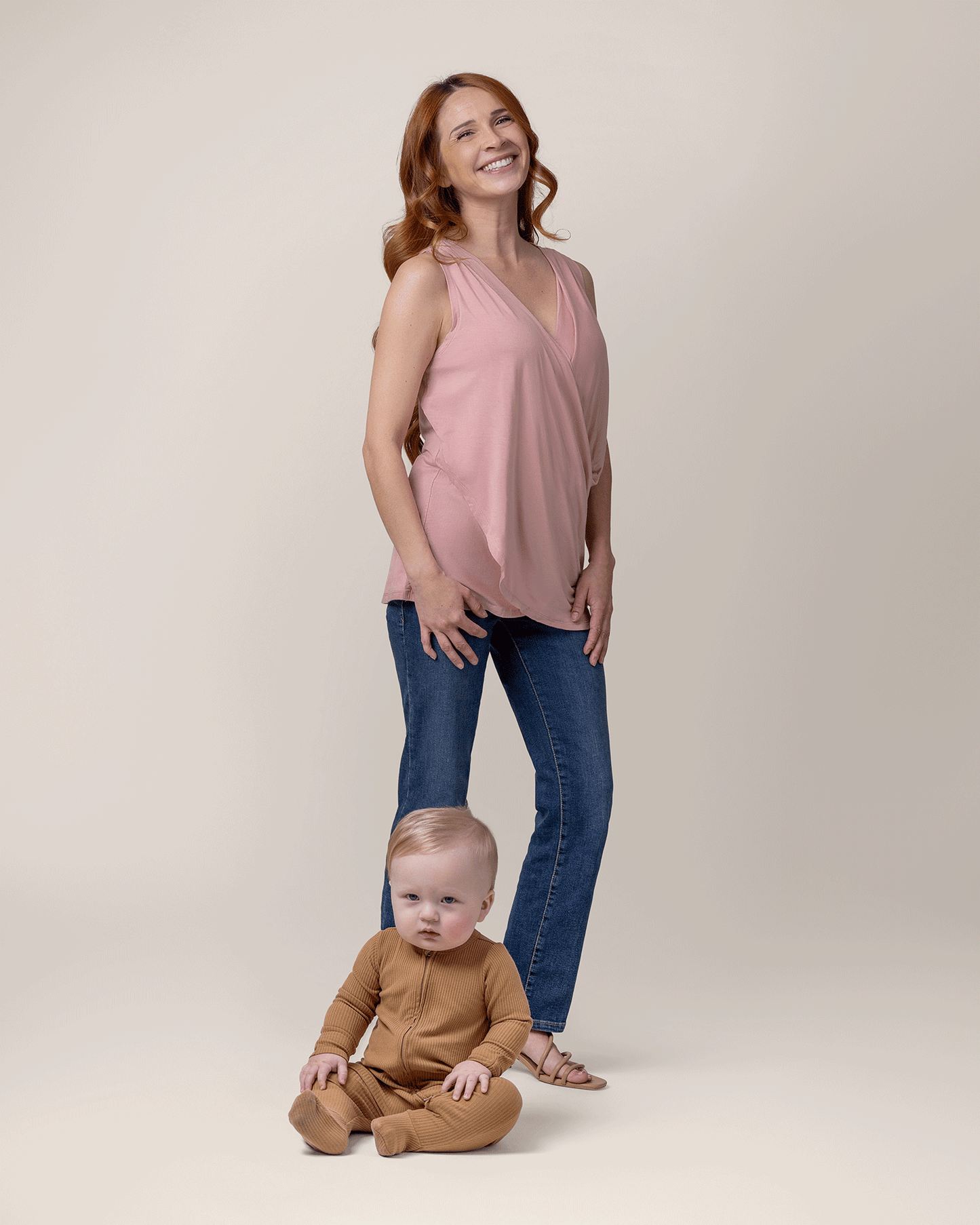 Model wearing the Bamboo Draped Nursing Tank in Light Mauve, paired with jeans and sandals, with baby sitting on the floor in front of her