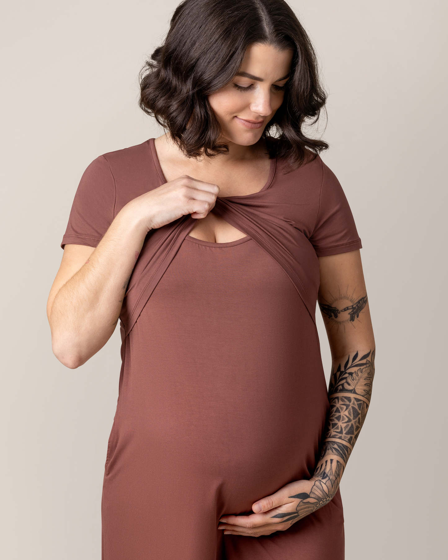 Close up of model wearing the Eleanora Bamboo Maternity & Nursing Dress in Redwood, lifting up top outer layer to show nursing access.