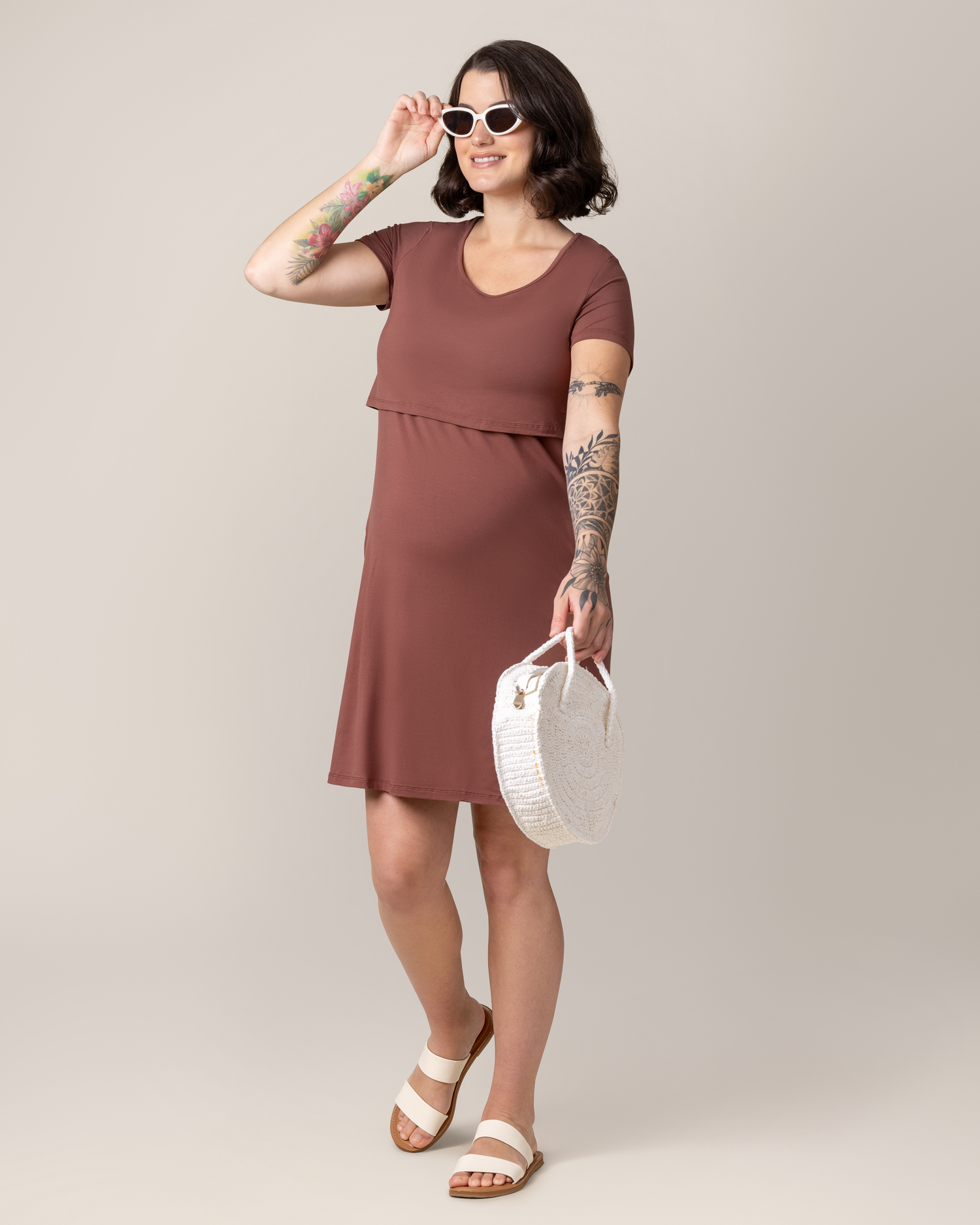 Model wearing the Eleanora Bamboo Maternity & Nursing Dress in Redwood, with sandals, sunglasses and holding bag