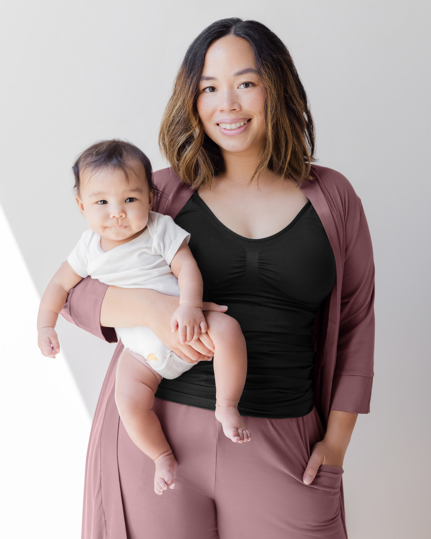 Model wearing the Simply Sublime Nursing Tank, paired with the Everyday Lounge Jogger in Twilight and Emmaline Robe in Twilight, holding baby