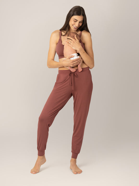 Front view of model wearing the Everyday Lounger Jogger in Redwood, holding baby against her.@model_info:Valerie is 5'10" and wearing a Small Long.