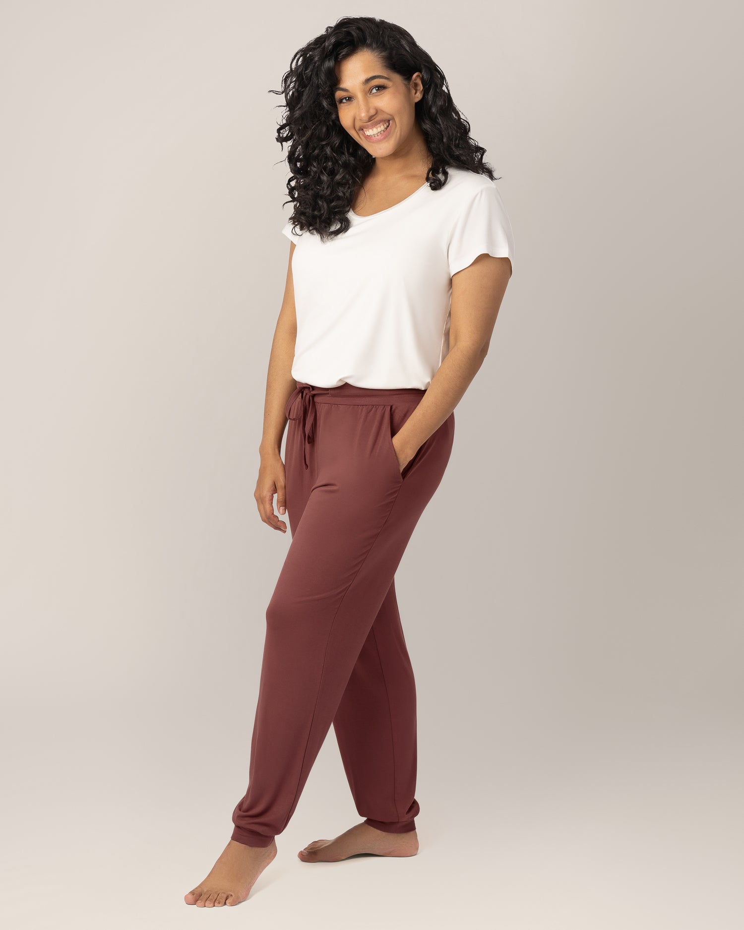 3/4 front view of model wearing the Everyday Lounger Jogger in Redwood, with one hand in pocket, paired with the Everyday Maternity & Nursing T-shirt in White. @model_info:Zakeeya is 5'2" and wearing a Small Regular.