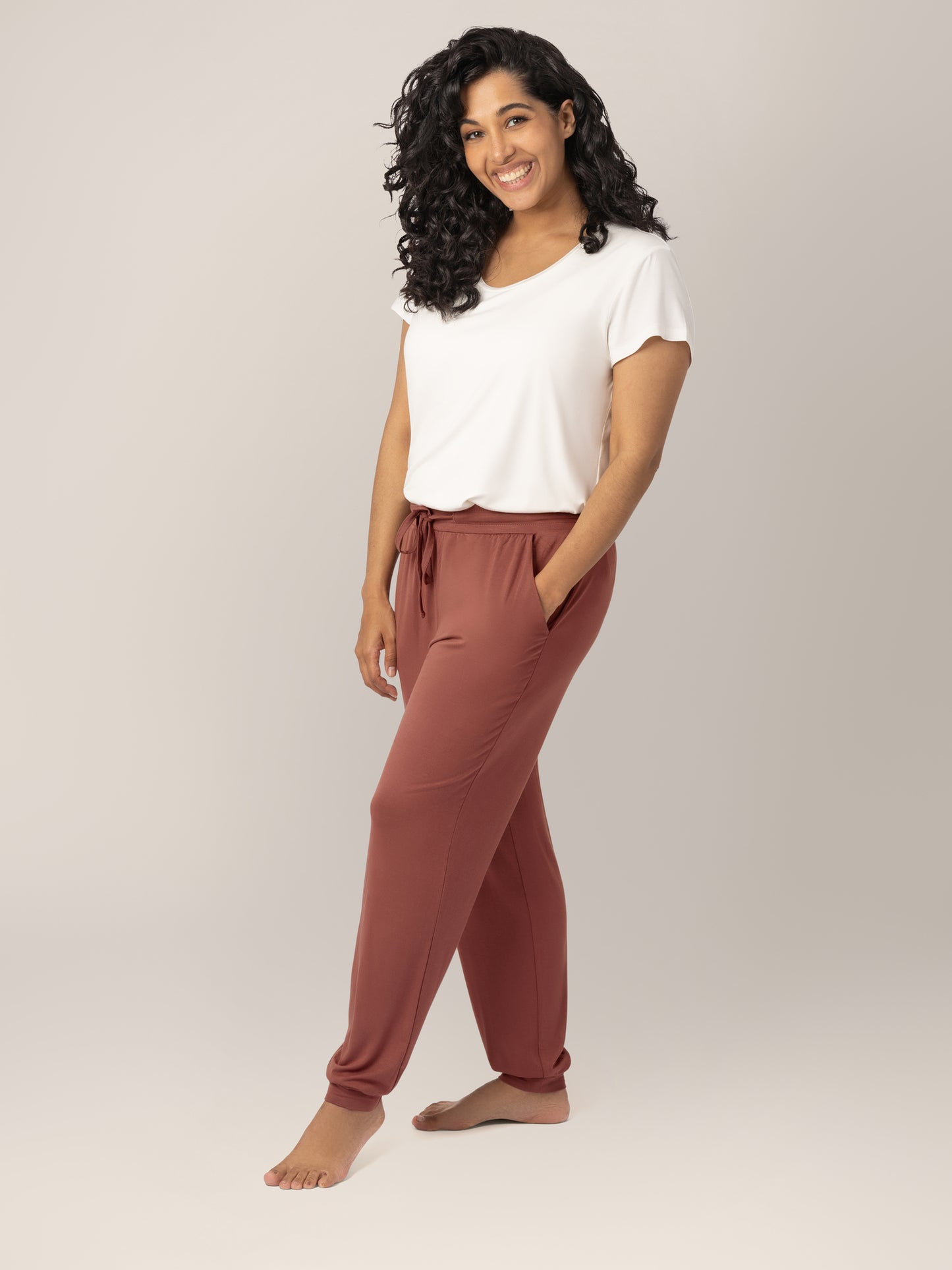 3/4 front view of model wearing the Everyday Lounger Jogger in Redwood, with one hand in pocket, paired with the Everyday Maternity & Nursing T-shirt in White. @model_info:Zakeeya is 5'2" and wearing a Small Regular.