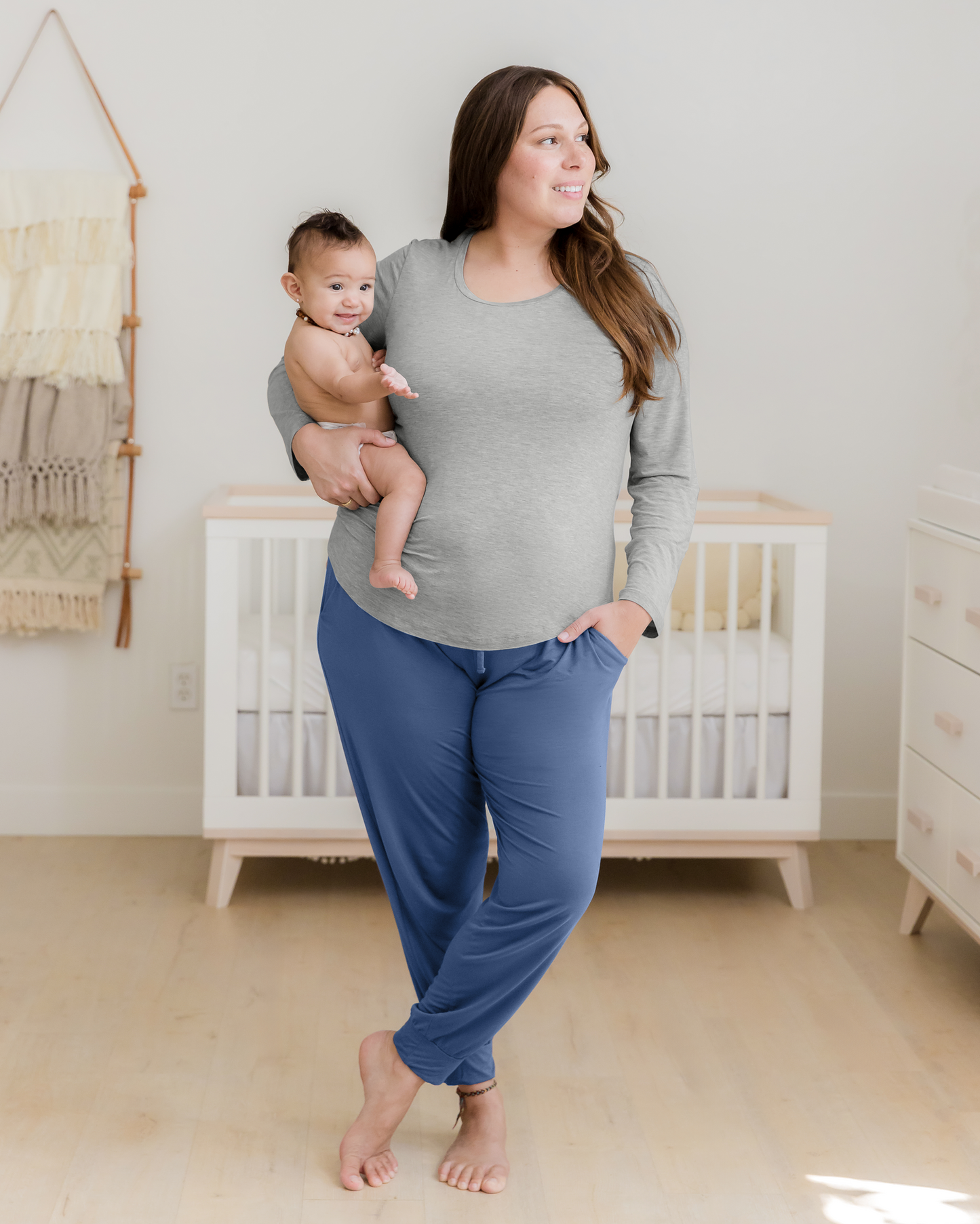 Model wearing the Bamboo Long Sleeve Nursing T-shirt in Grey Heather paired with Everyday Lounge Jogger in Slate Blue, holding baby