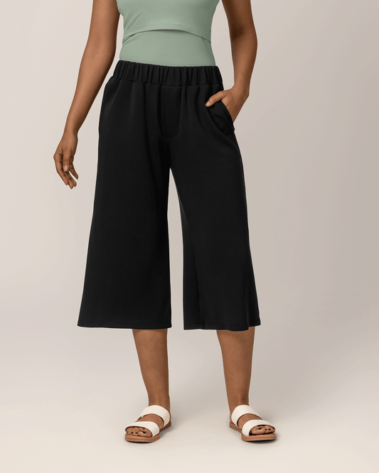 Front view of model wearing Evie Maternity & Postpartum Pull-On Cropped Pant in black, with a hand in the pocket @model_info:Marisa is wearing a Small.