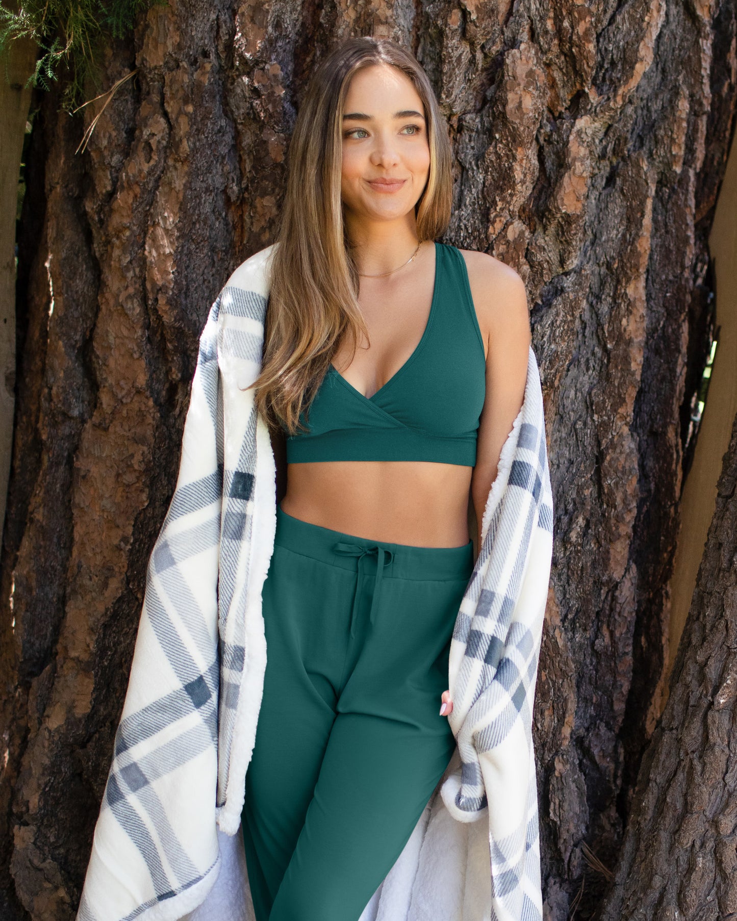 Front view of model outside wearing the French Terry Racerback Nursing & Sleep Bra in Evergreen, paired with matching Everyday Lounge Jogger, and with blanket wrapped around her