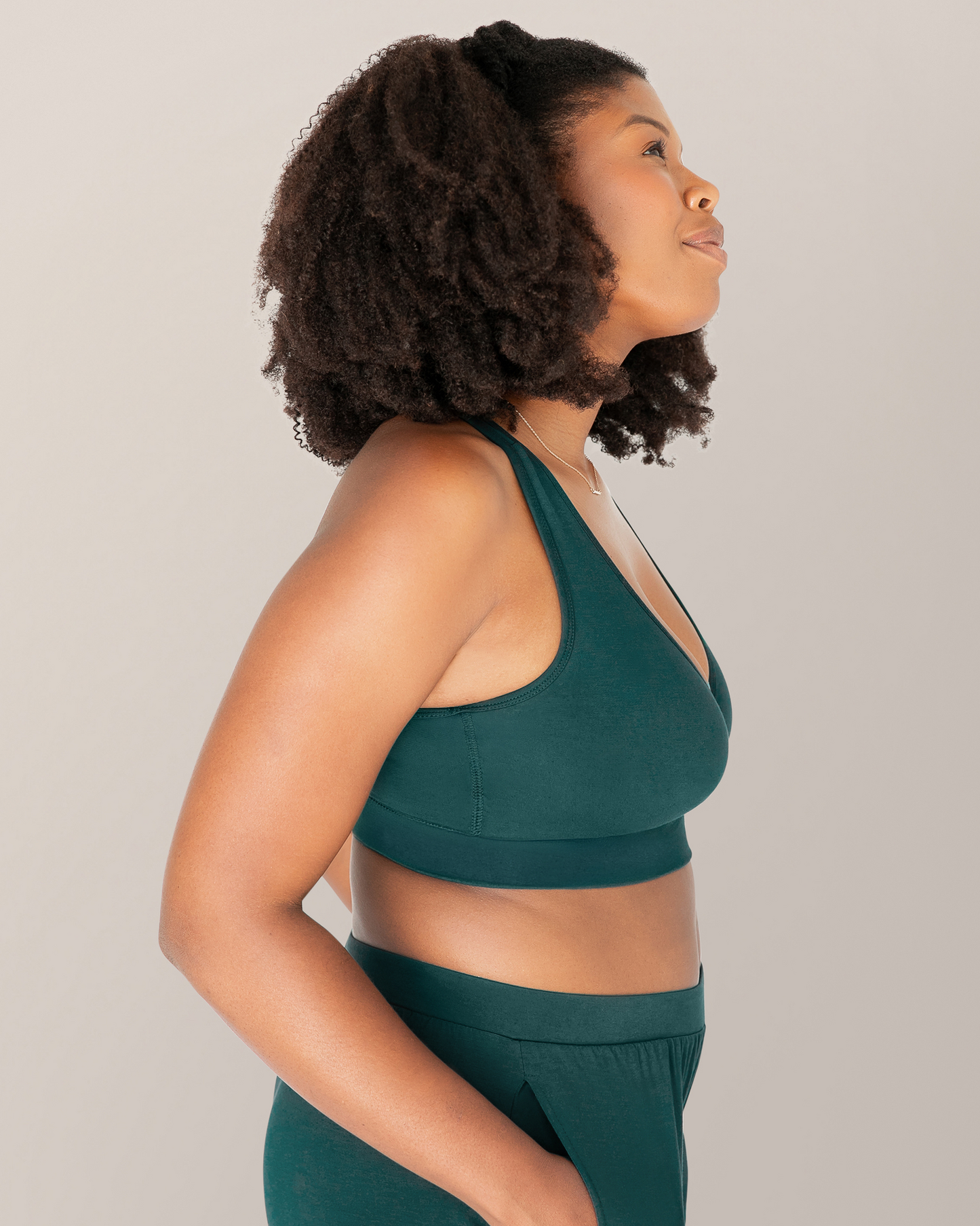 Side view of model outside wearing the French Terry Racerback Nursing & Sleep Bra in Evergreen