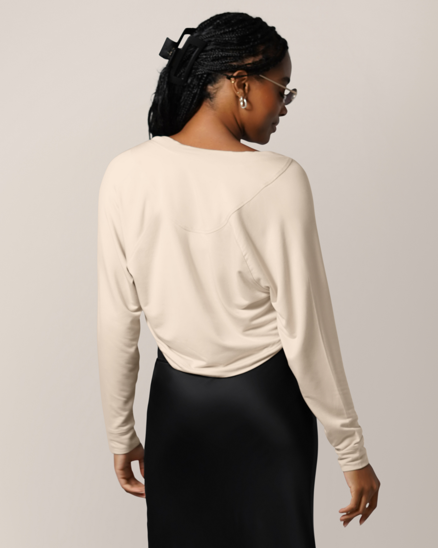 Front view of model wearing the French Terry Cardigan Shrug in Oatmeal, paired with a black skirt