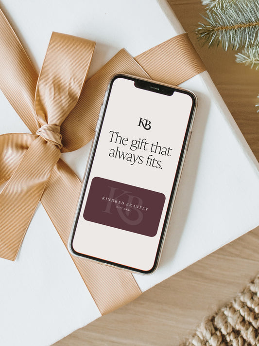 Kindred Bravely digital gift card on phone sitting on top of wrapped gift