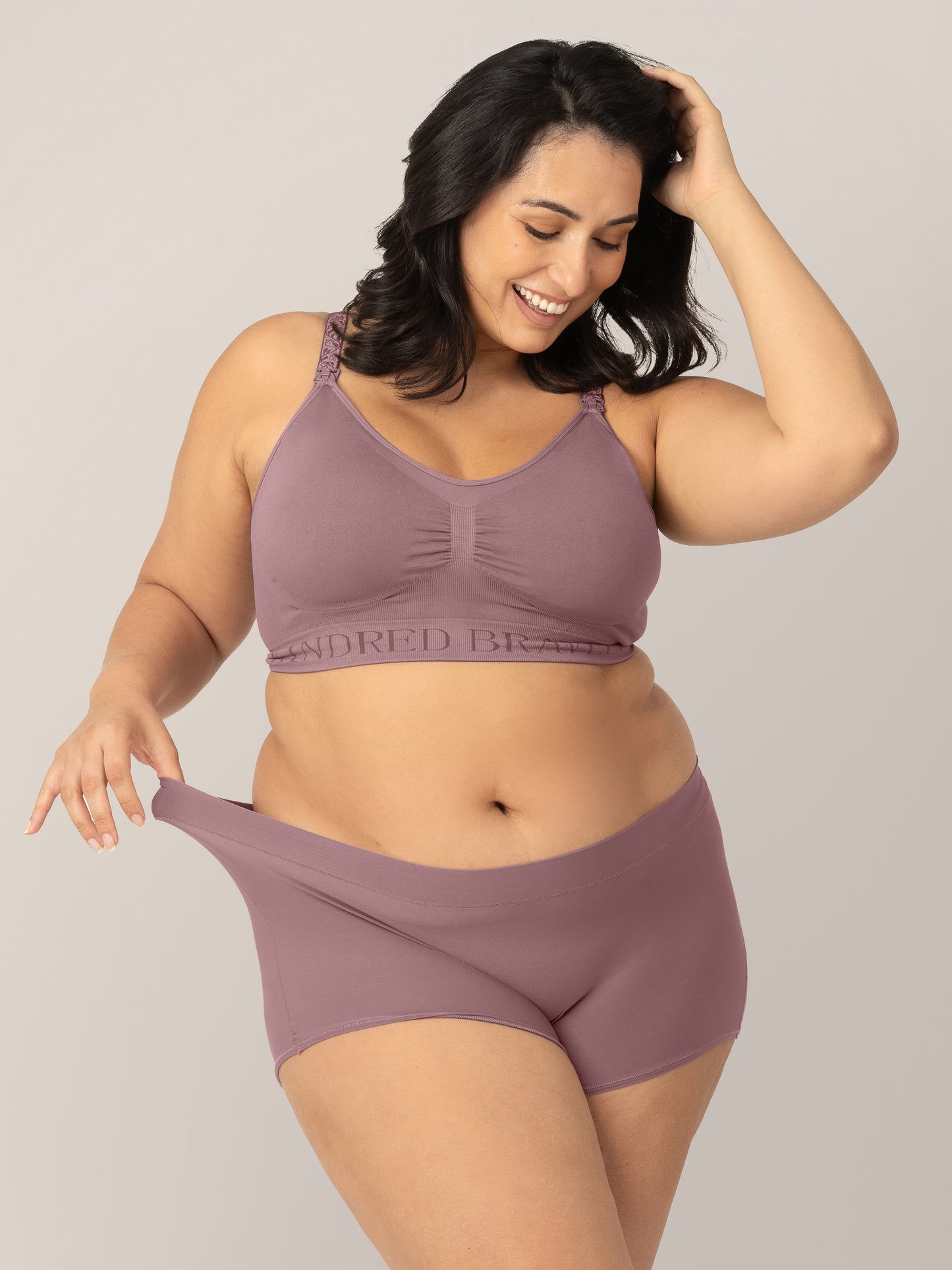 Model wearing the Twilight Grow with Me™ Maternity & Postpartum Boyshort and pulling the waistband to show stretch. @model_info: Connie is wearing an X-Large.