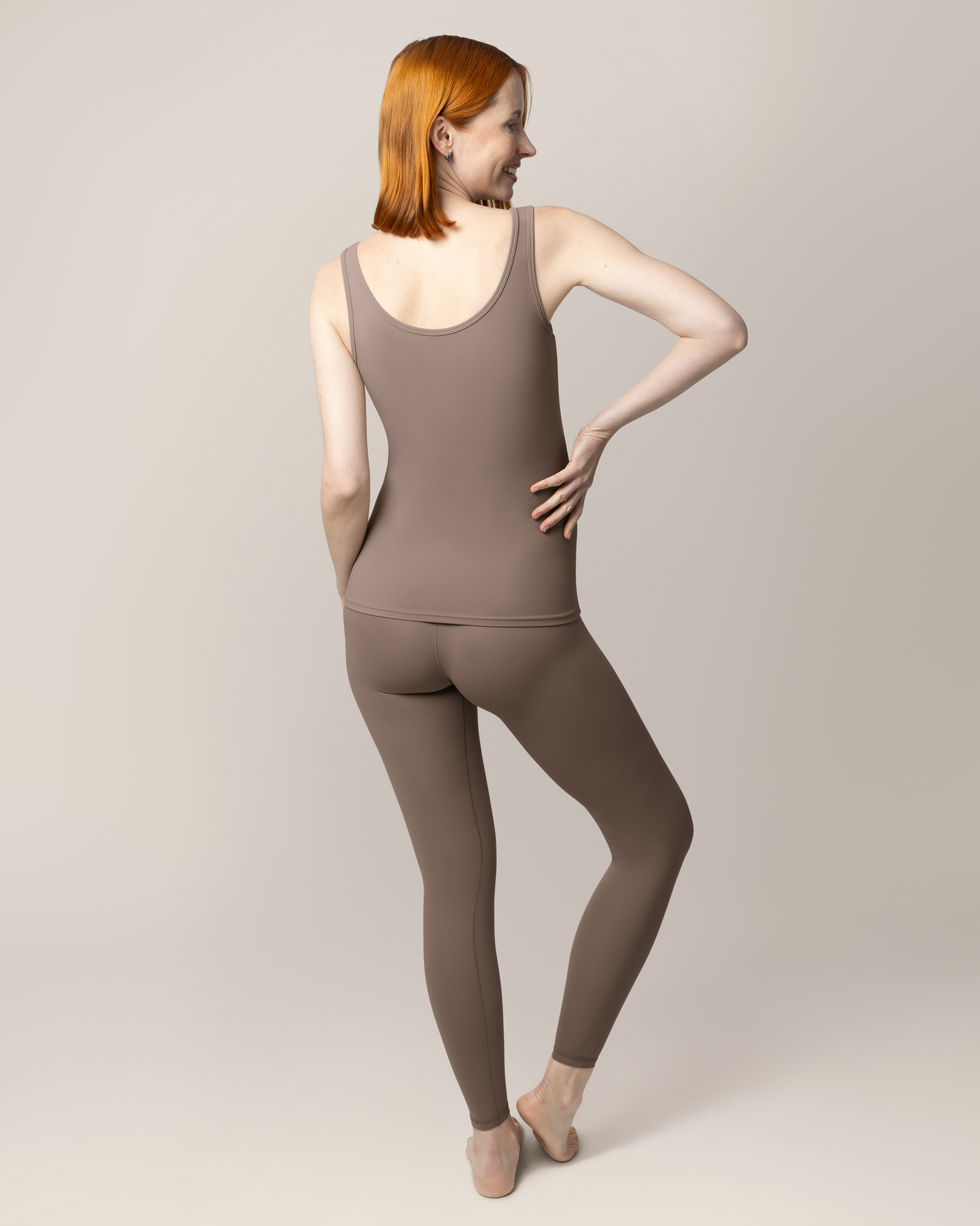 Back view of pregnant model wearing the Grow with Me™ Maternity & Postpartum Legging in Taupe paired with matching Grow with Me™ Maternity & Nursing Tank