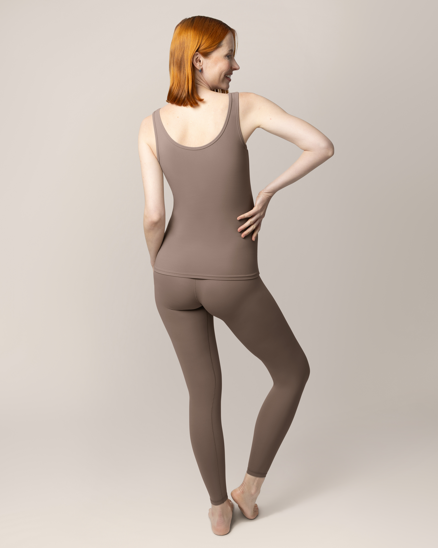 Back view of pregnant model wearing the Grow with Me™ Maternity & Postpartum Legging in Taupe paired with matching Grow with Me™ Maternity & Nursing Tank