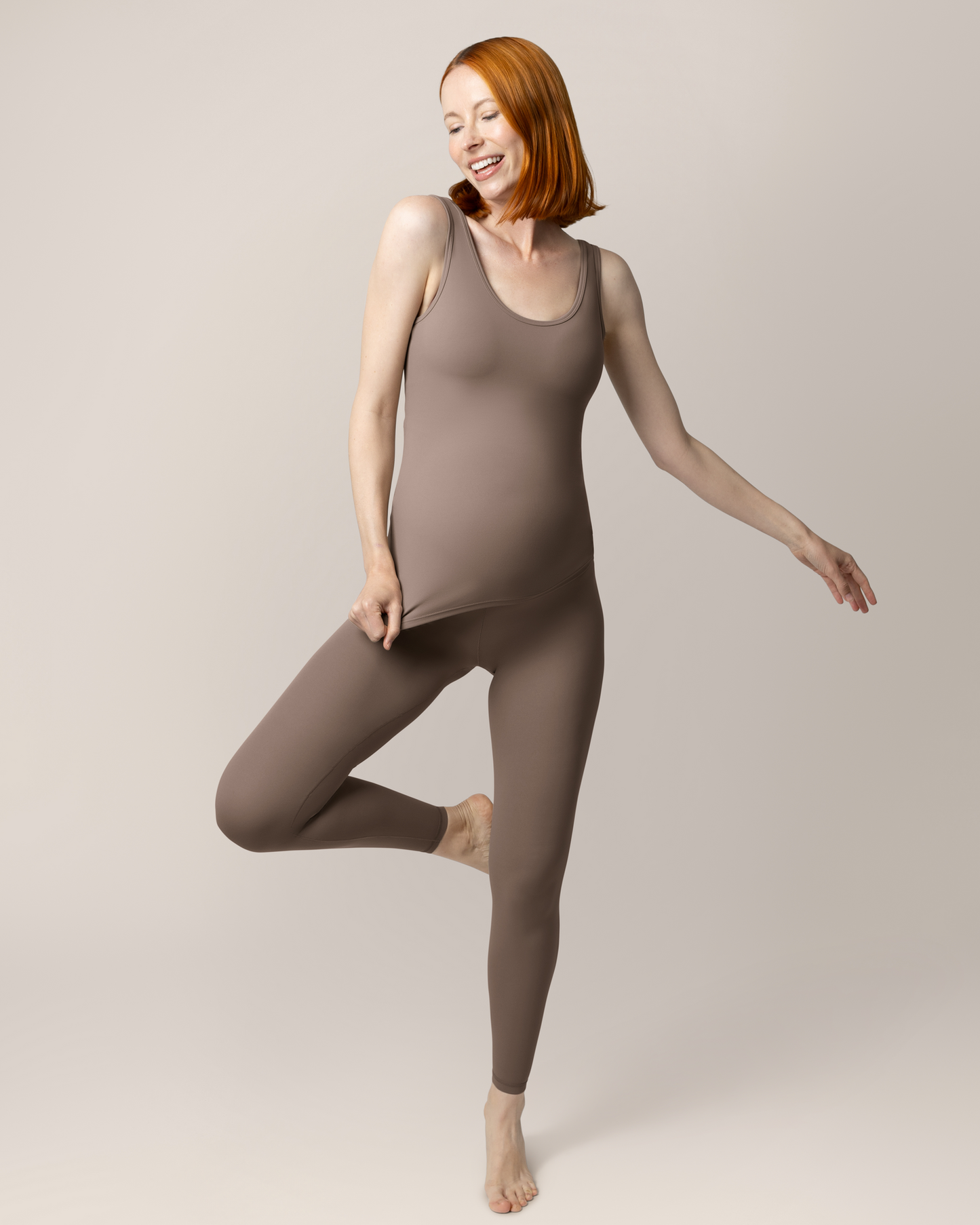 Front view of pregnant model wearing the Grow with Me™ Maternity & Postpartum Legging in Taupe paired with matching Grow with Me™ Maternity & Nursing Tank