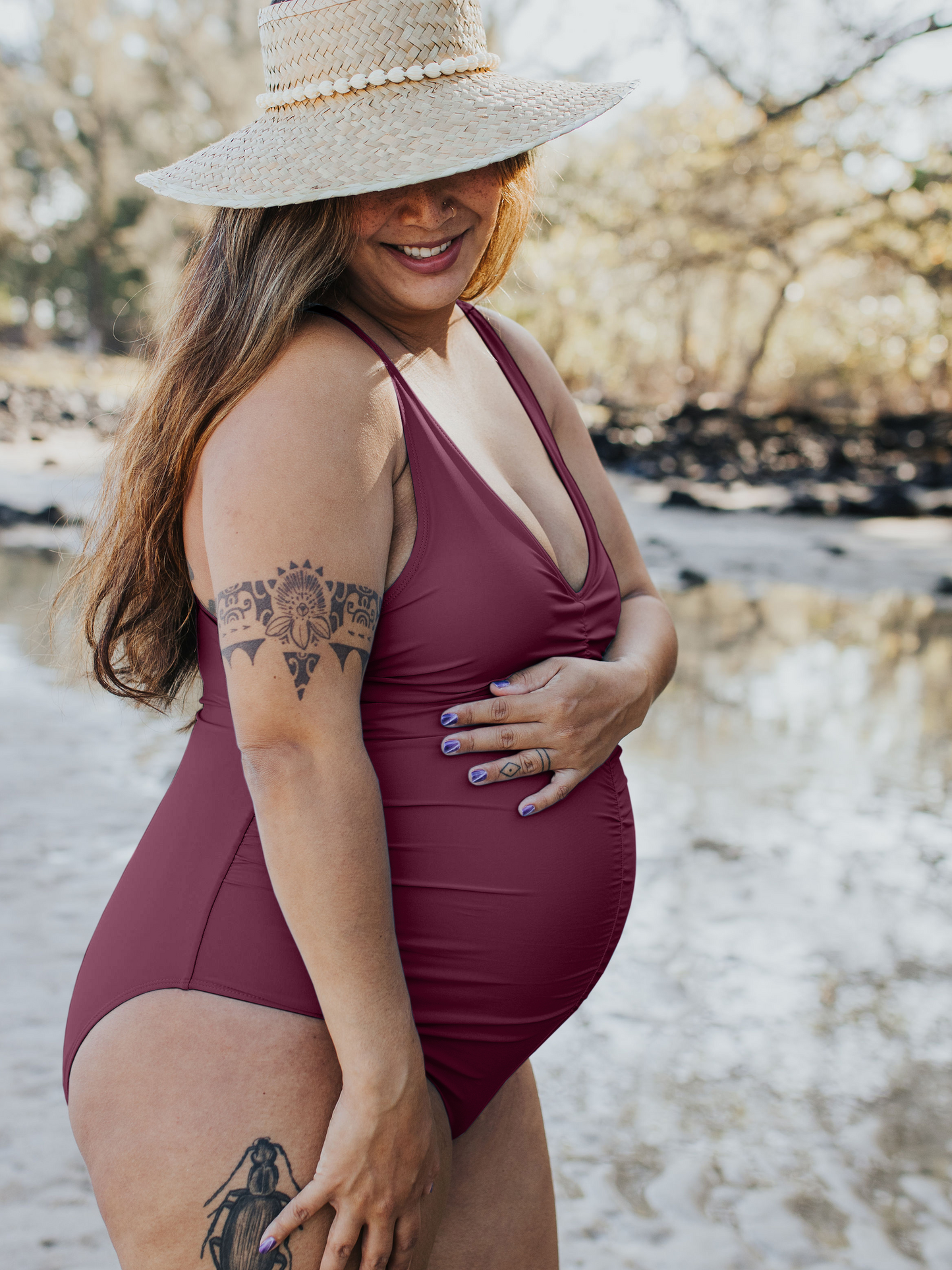 Side view of pregnant model outside wearing the Gathered Maternity One Piece Swimsuit in Maroon. @model_info:Kyllie is wearing an X-Large.