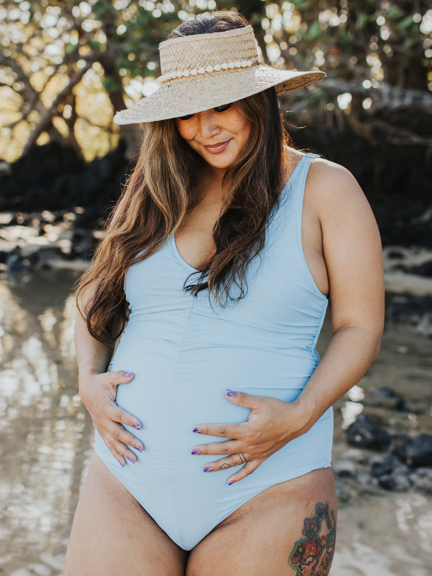 Front view of pregnant model wearing the Gathered Maternity One Piece Swimsuit in Light Blue with hands on belly