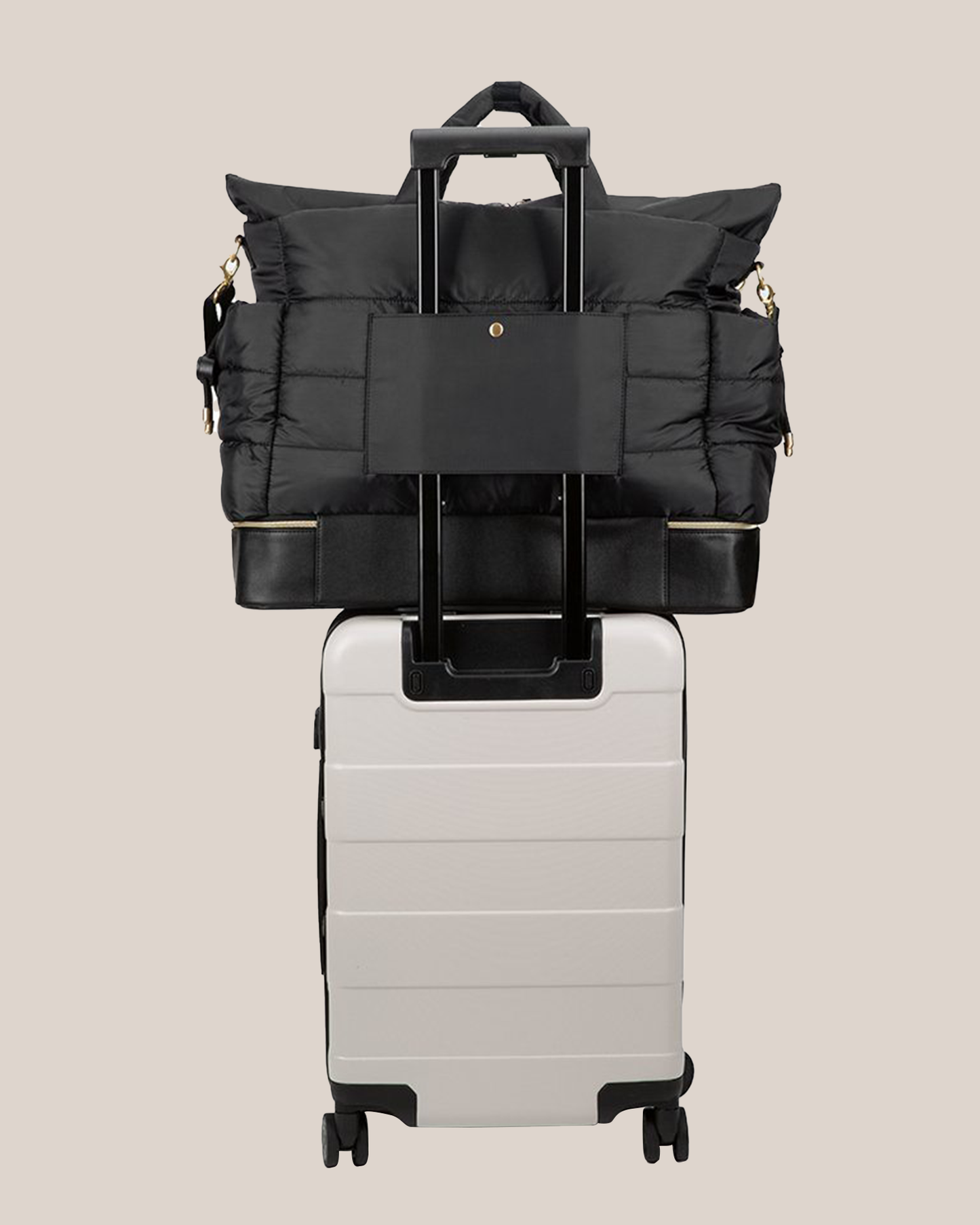 Back view of the Itzy Ritzy - Dream Weekender™ Hospital & Travel Bag in Midnight Black on top of suitcase, hooked onto handle