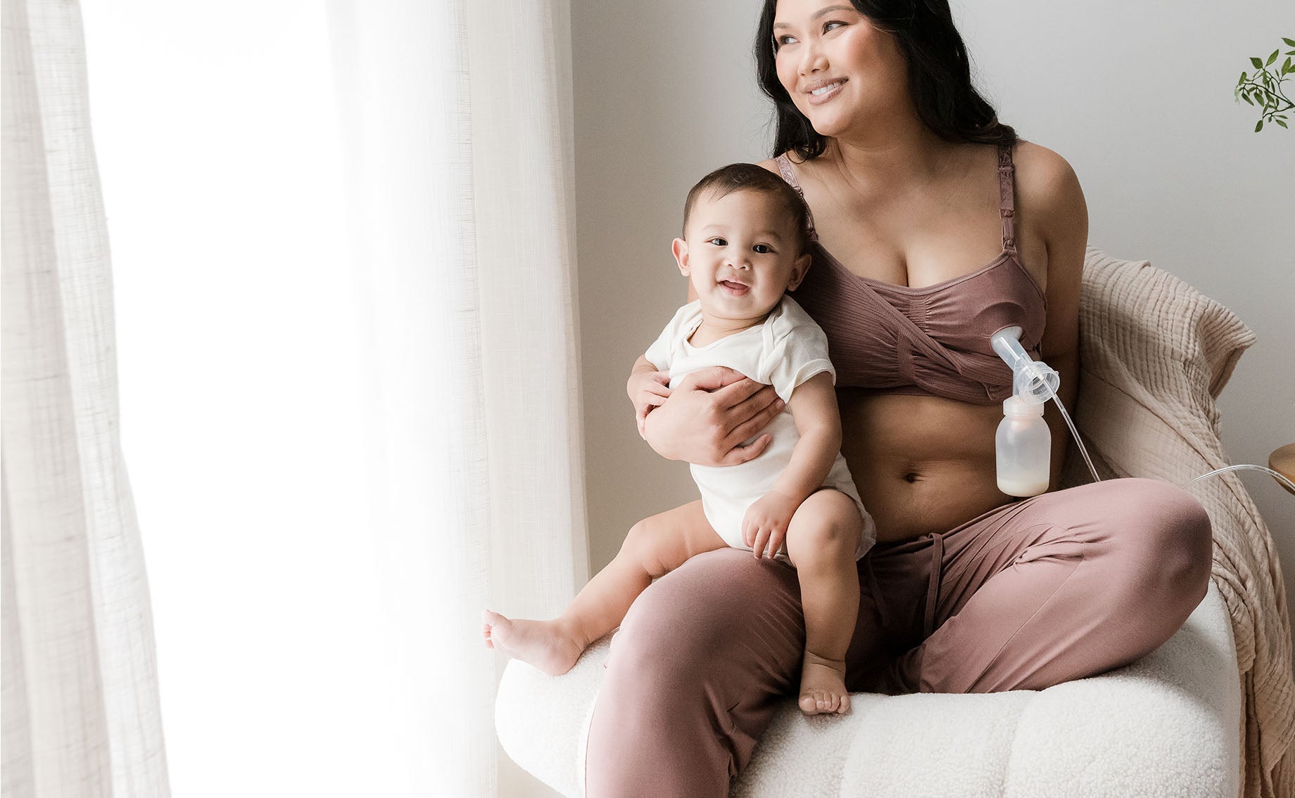 Model wearing the Sublime® Hands-Free Pumping & Nursing Bra in Twilight, pumping and holding baby on lap